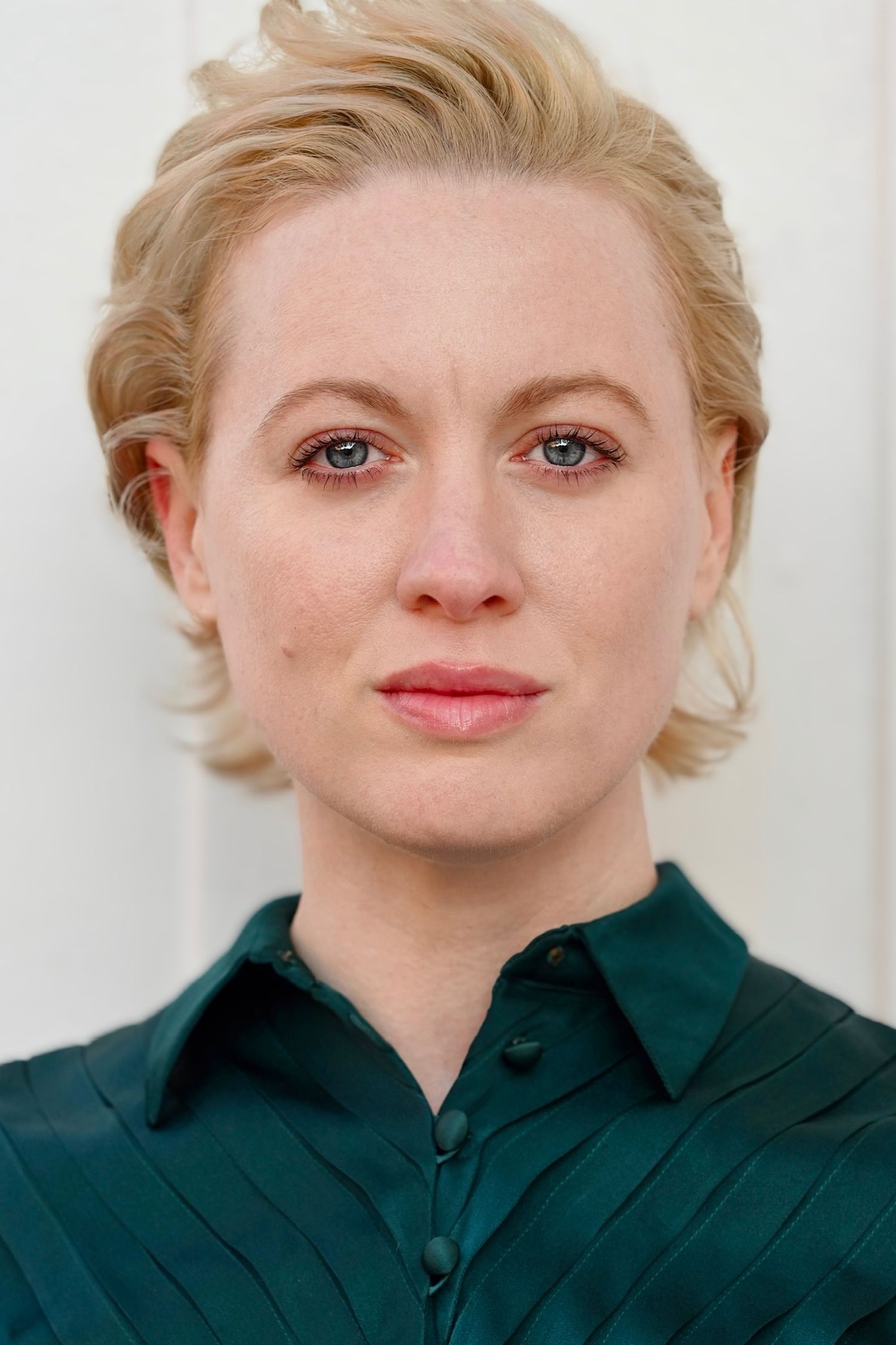 Professional headshot series with green collared shirt against white background.