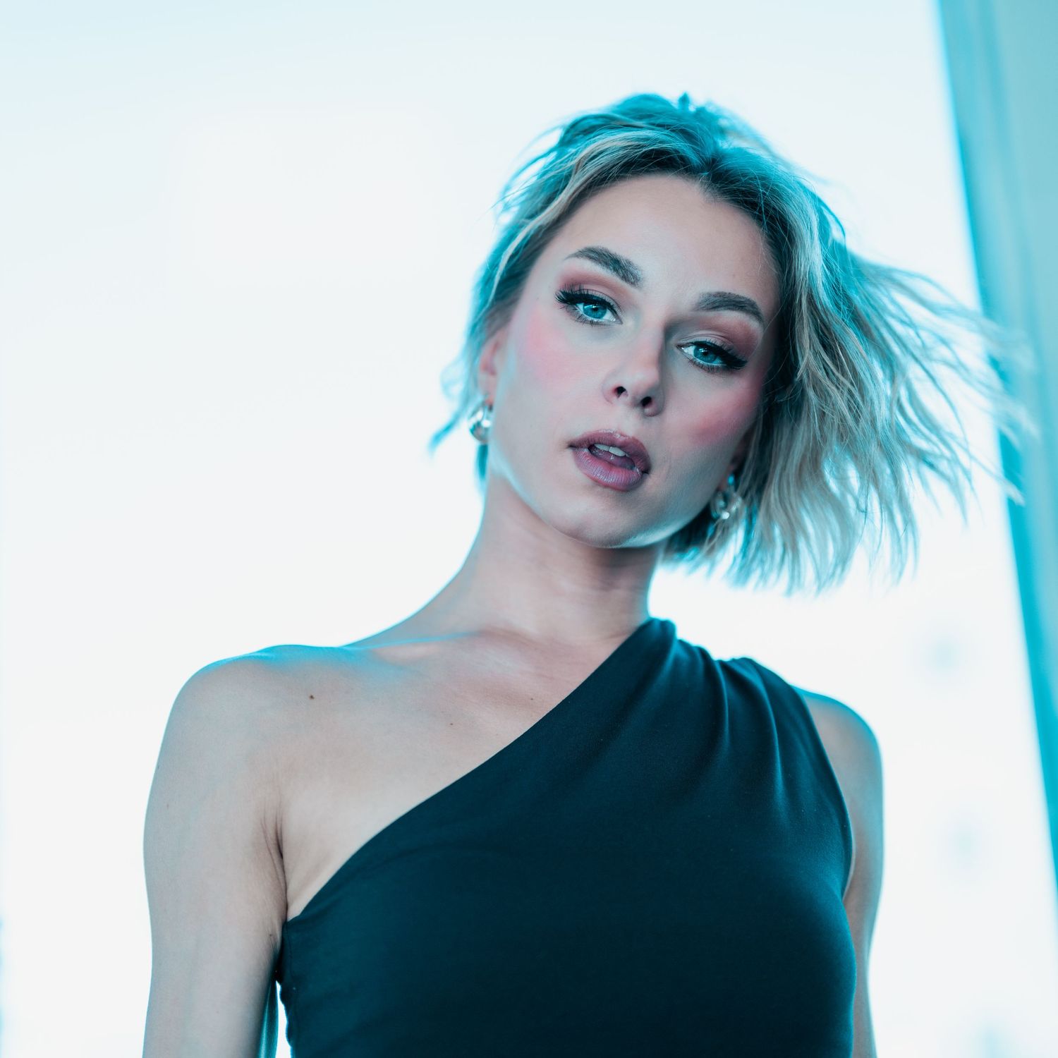 Fashion photography with cool blue tones showing elegant poses in a black asymmetrical top.