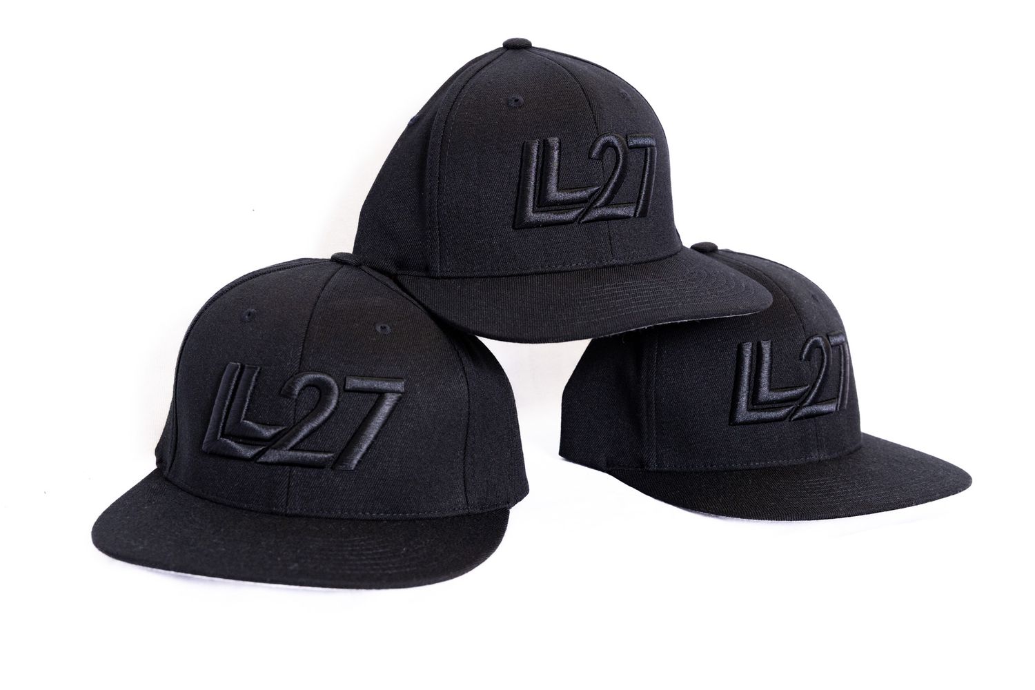 Three black snapback caps with embroidered LL27 logo displayed together on white background.