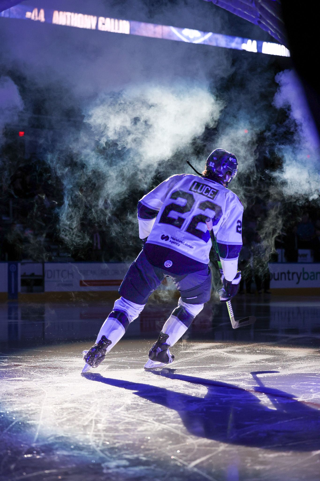 Hockey player #22 skating onto ice rink through dramatic smoke and purple lighting during player introduction ceremony.