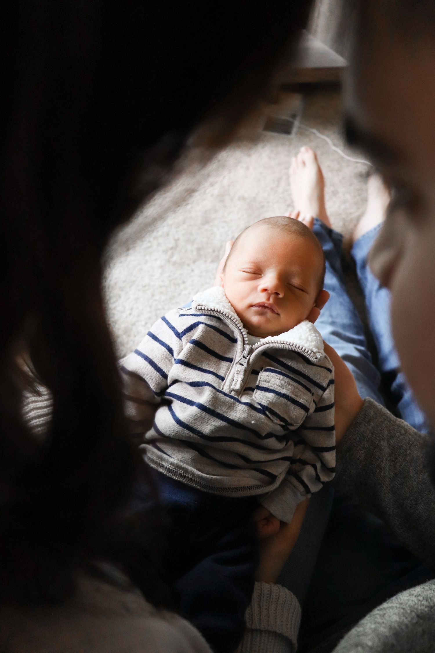 Newborn baby swaddled and sleeping peacefully while being held during cozy in-home session in Kennewick WA