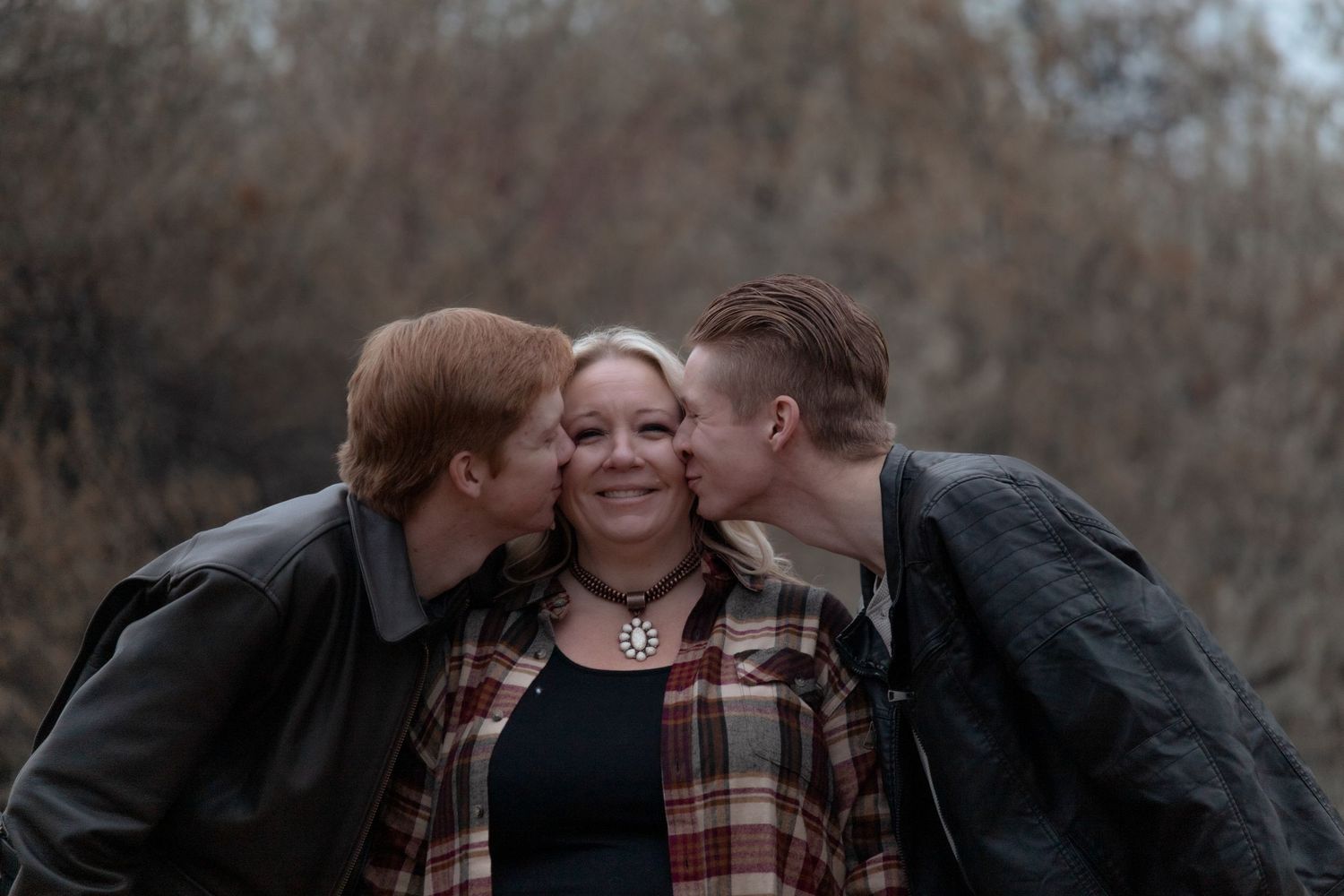 Grown sons playfully kissing their mom on the cheeks during a heartfelt family session in Kennewick WA