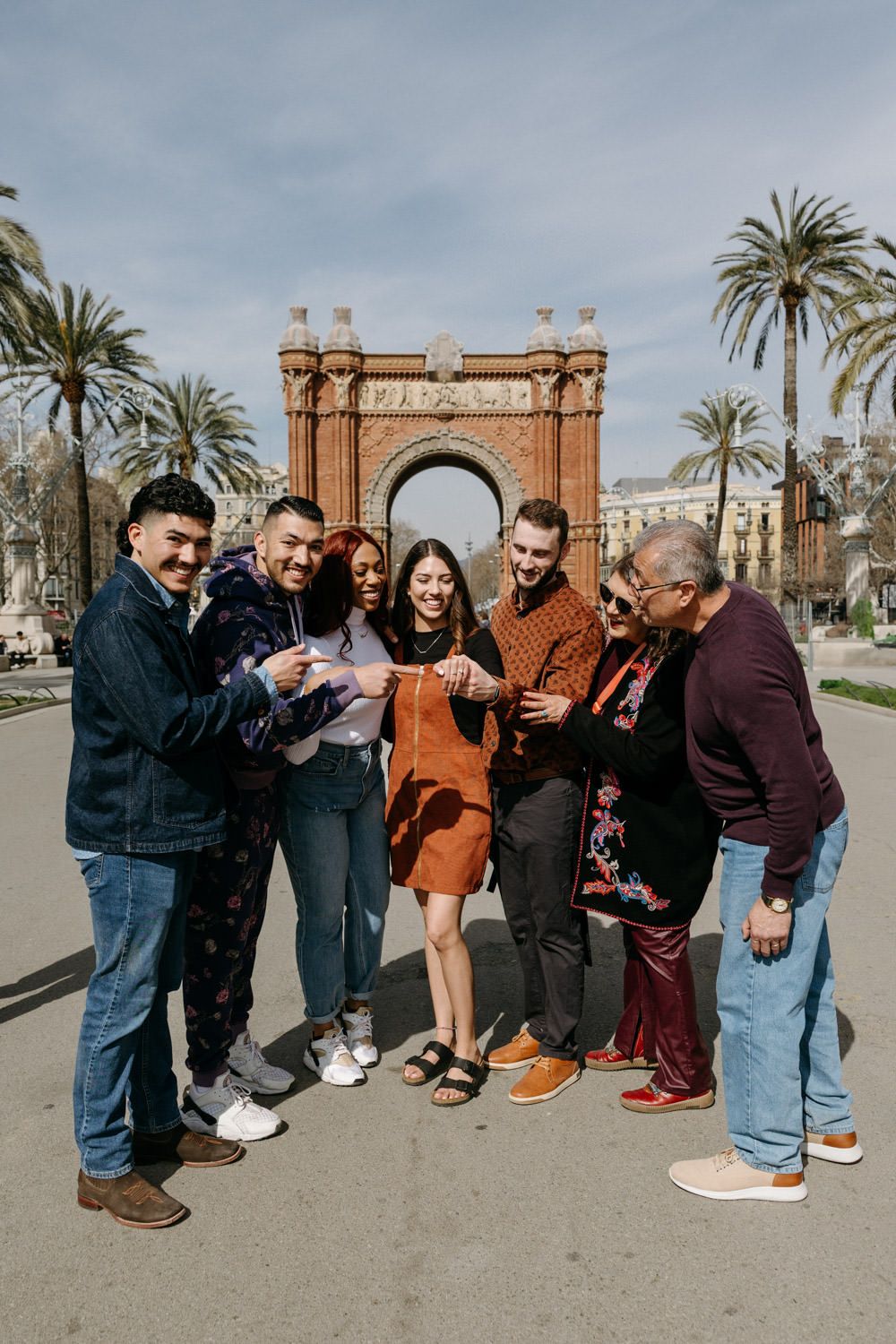 Group poses playfully together in front of historic Arc de Triomf in Barcelona.