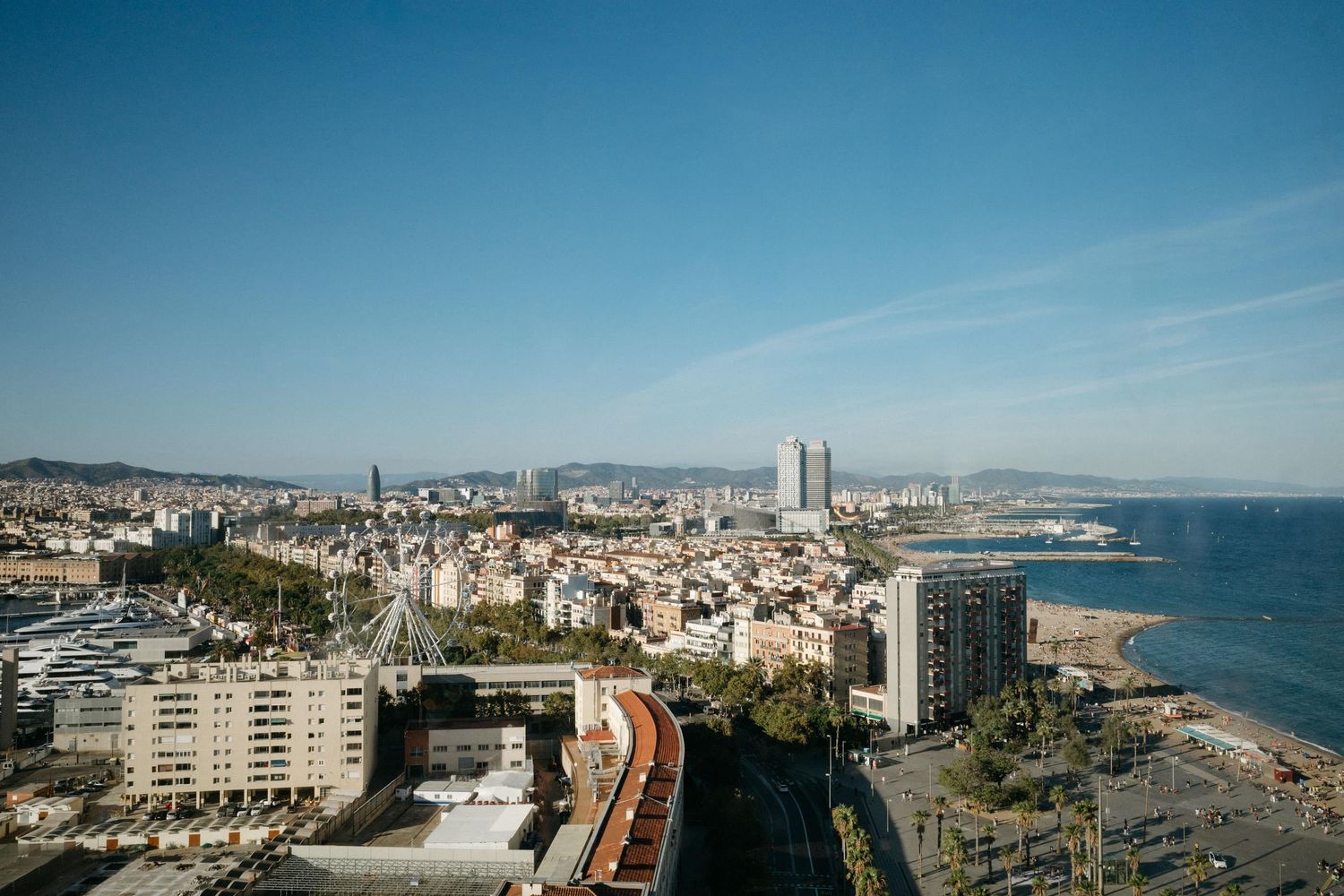 Aerial view of Barcelona's coastline and city skyline on a clear sunny day.