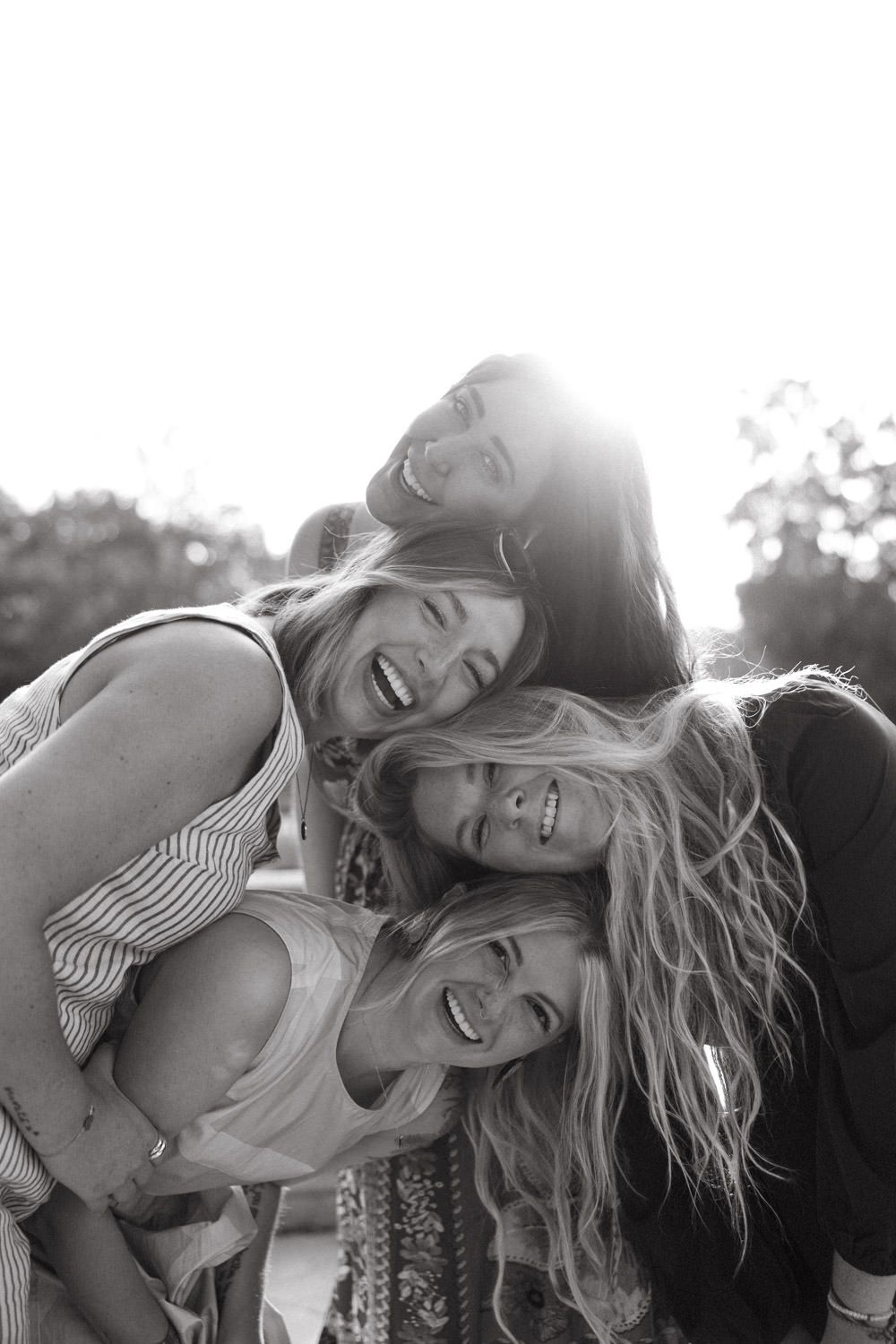 Candid lifestyle portrait of friends laughing together in warm sunlight.
