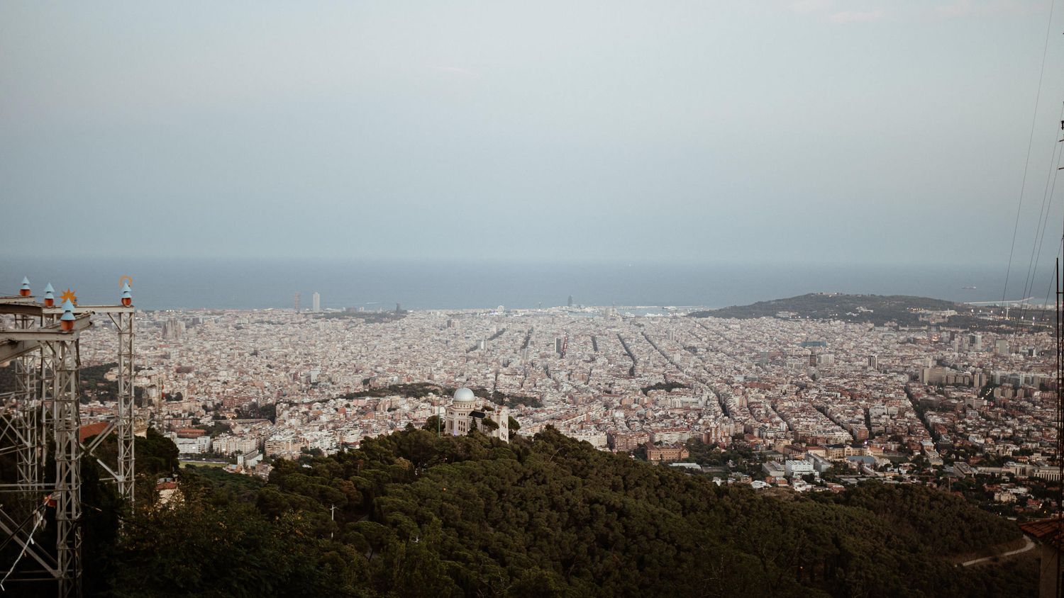 Wide aerial view of Barcelona's urban landscape extending to the Mediterranean Sea.