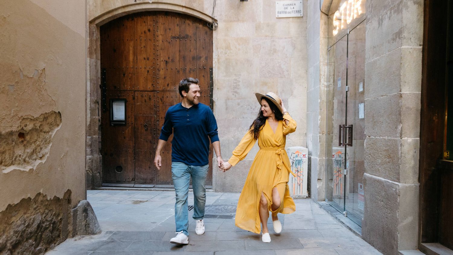 A couple explores narrow medieval streets lined with stone architecture.