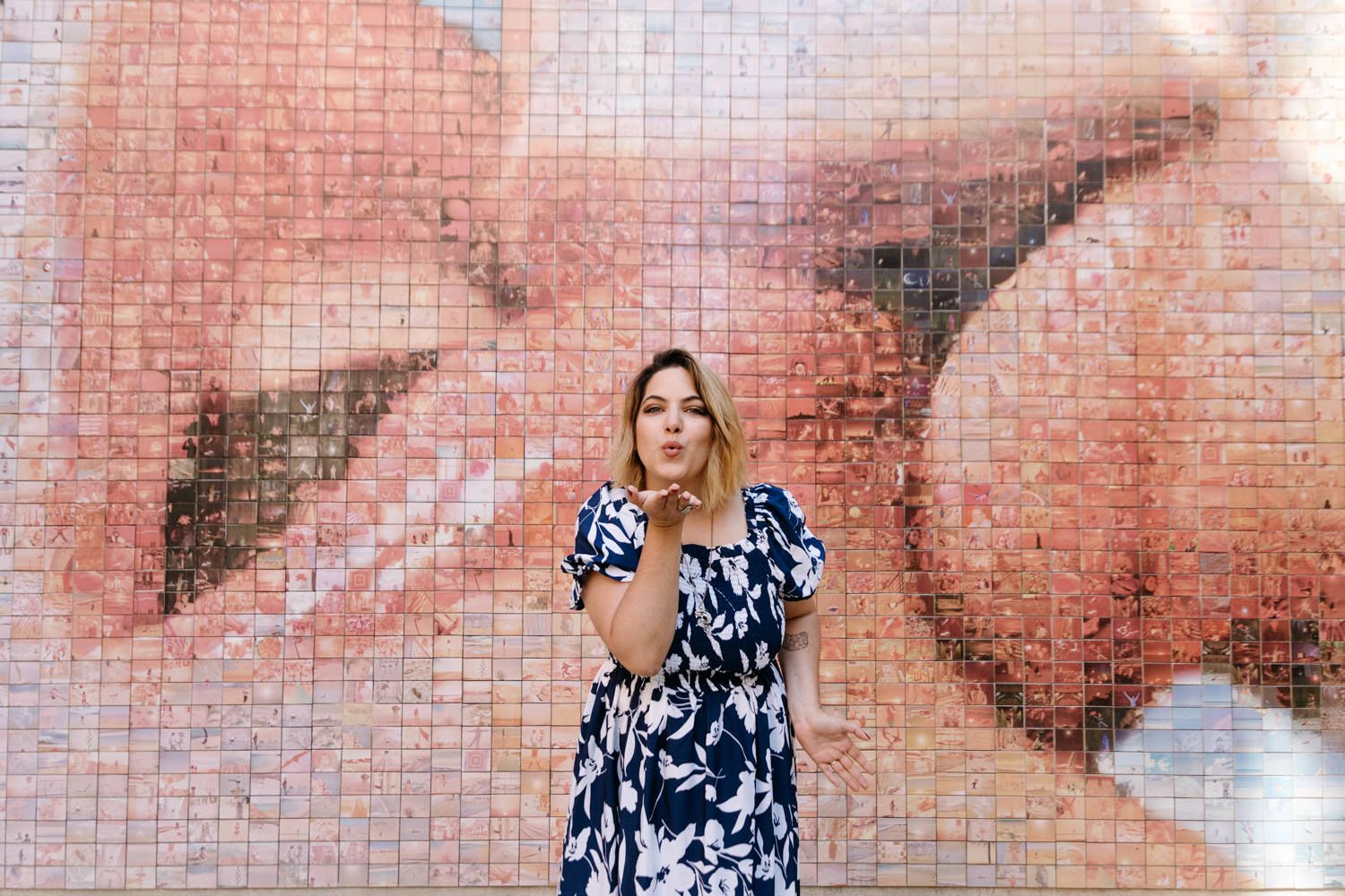 Couple sharing an intimate moment against a pink brick wall background.