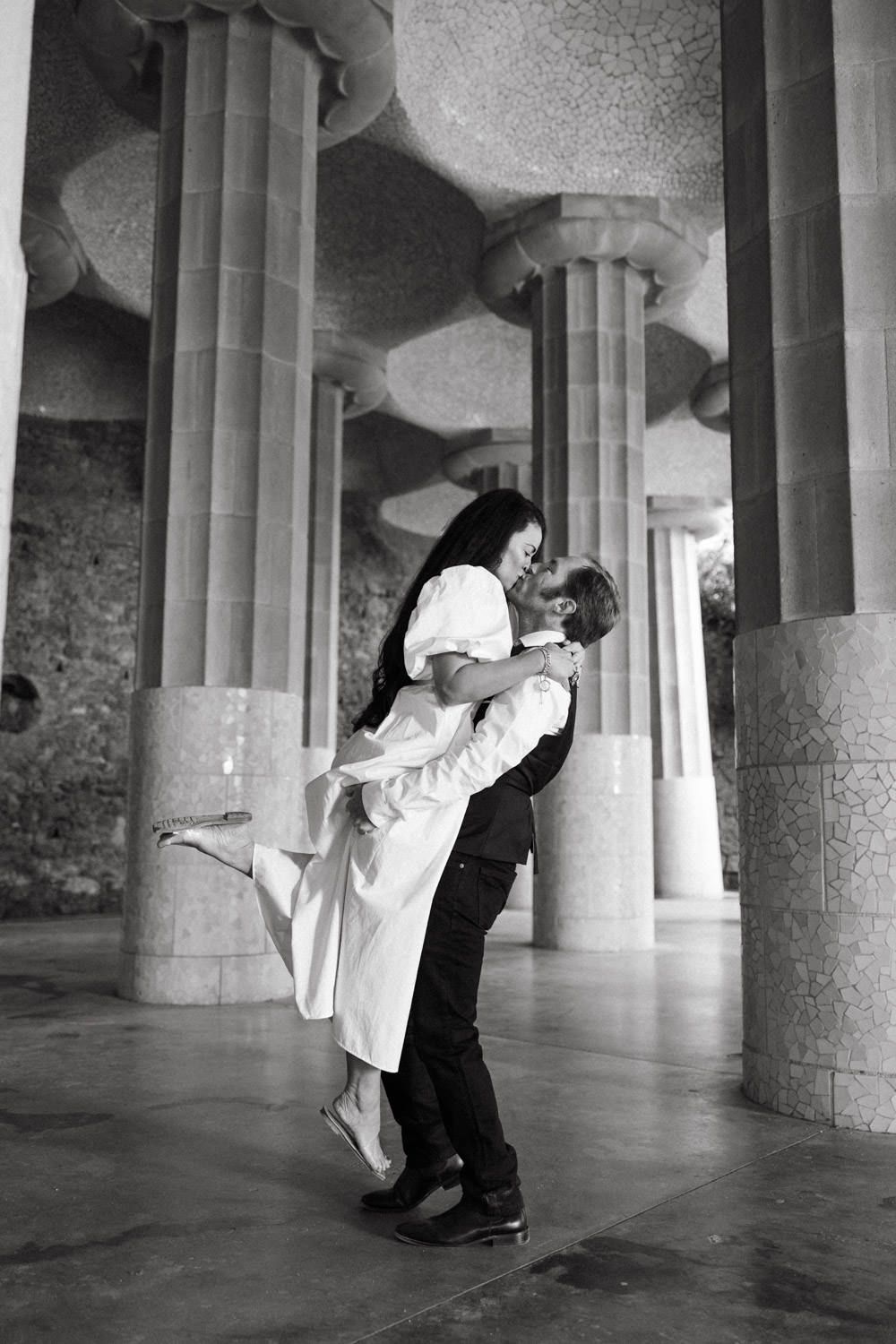 Couple performs romantic dance moves between stone columns in a historic building.