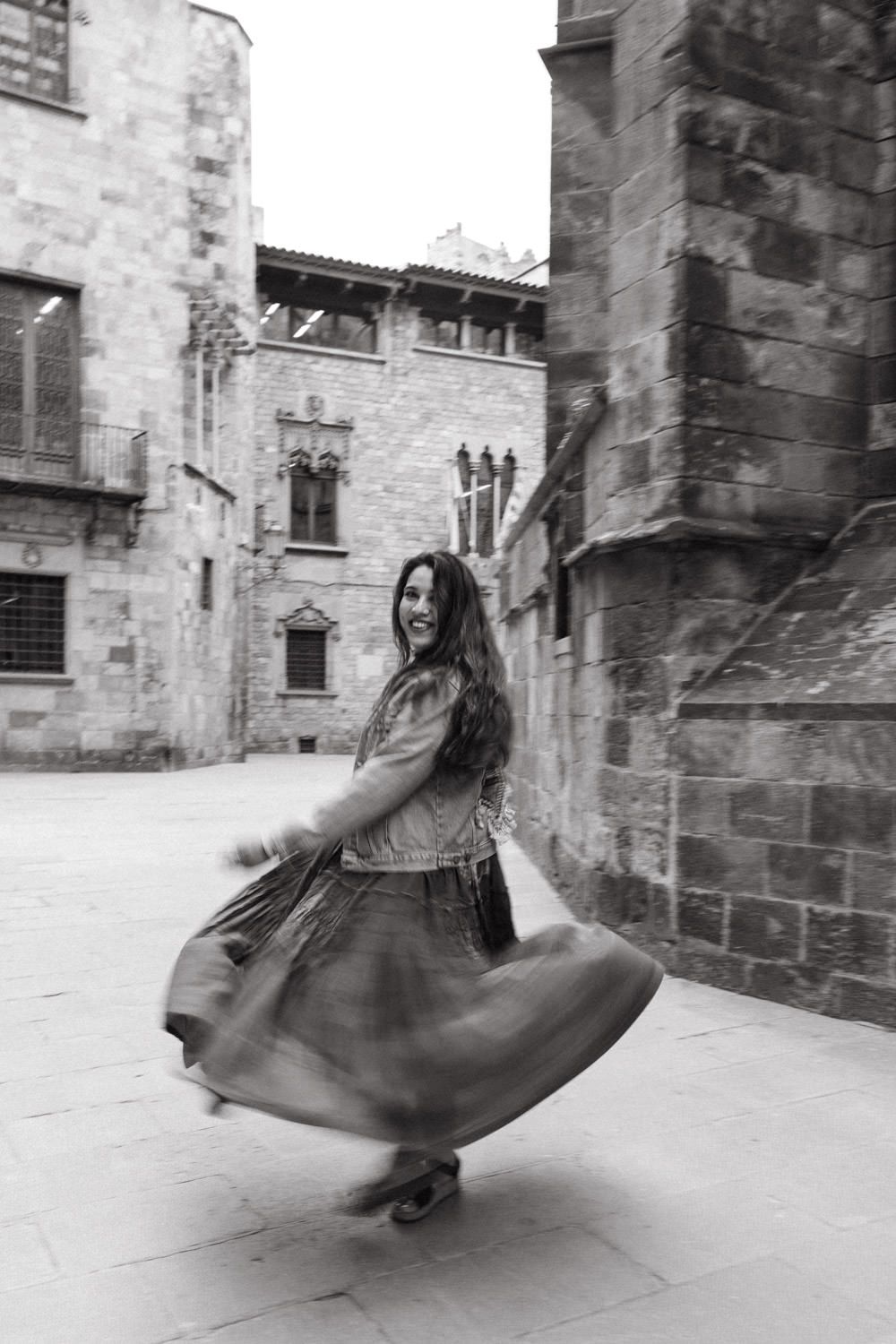 A twirling dress creates motion blur against medieval stone walls in Barcelona.