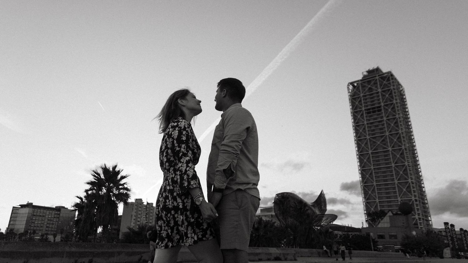 Silhouettes of people against a cityscape with tall buildings at sunset.