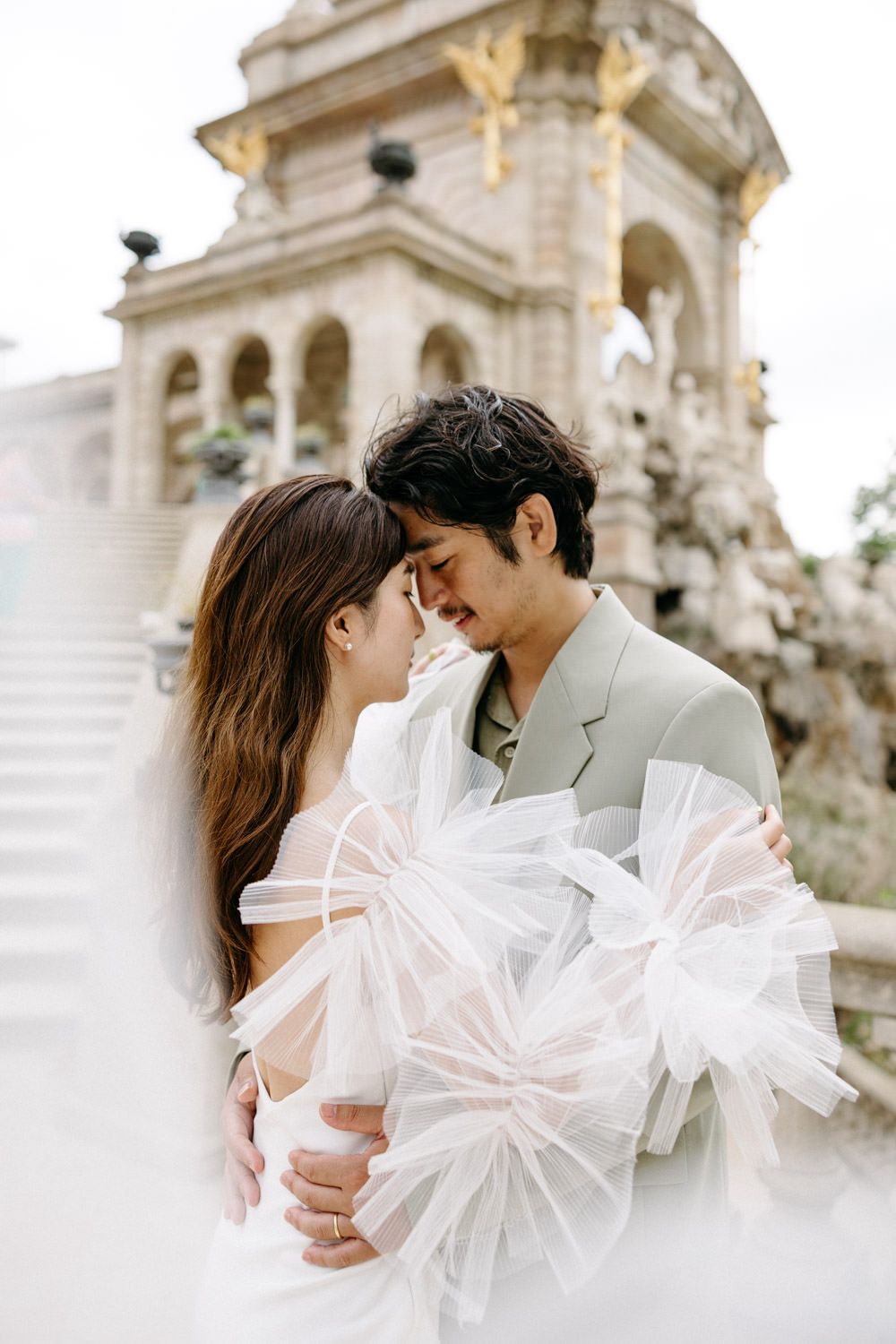 Romantic couple shares intimate moments near ornate architectural details in elegant attire.