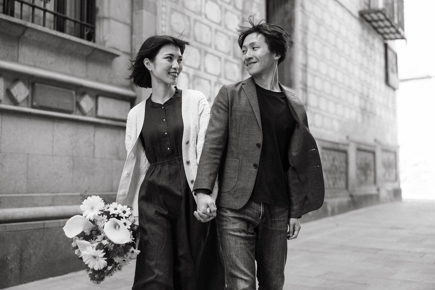 A couple walks hand in hand through historic stone streets in Barcelona's Gothic Quarter.