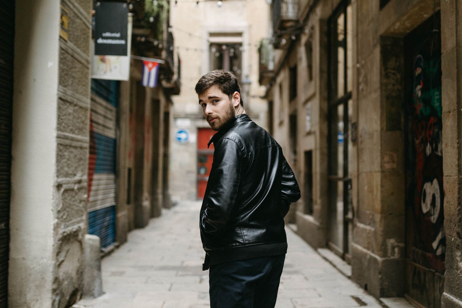 Person walking through narrow medieval alleyway between weathered stone buildings.