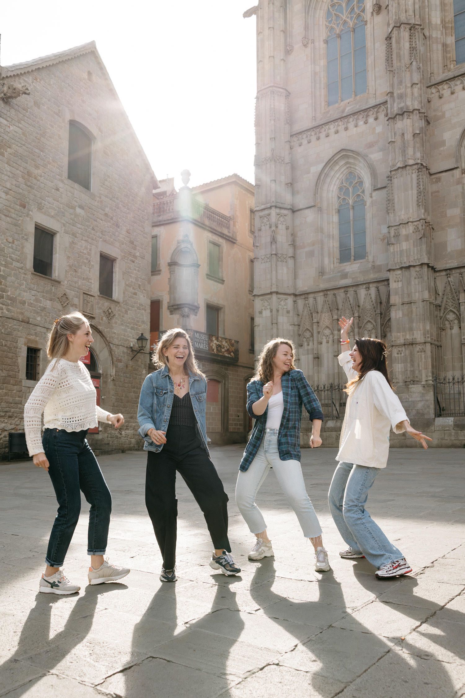 Friends dancing and having fun in front of a Gothic cathedral in sunlight.