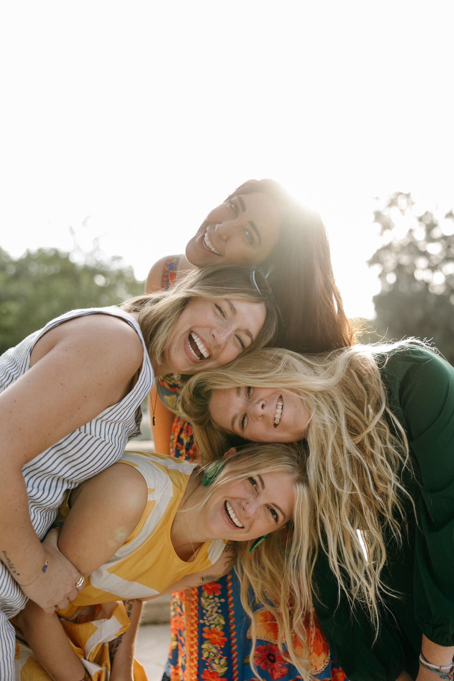 Candid sunlit photo of friends laughing and embracing outdoors.