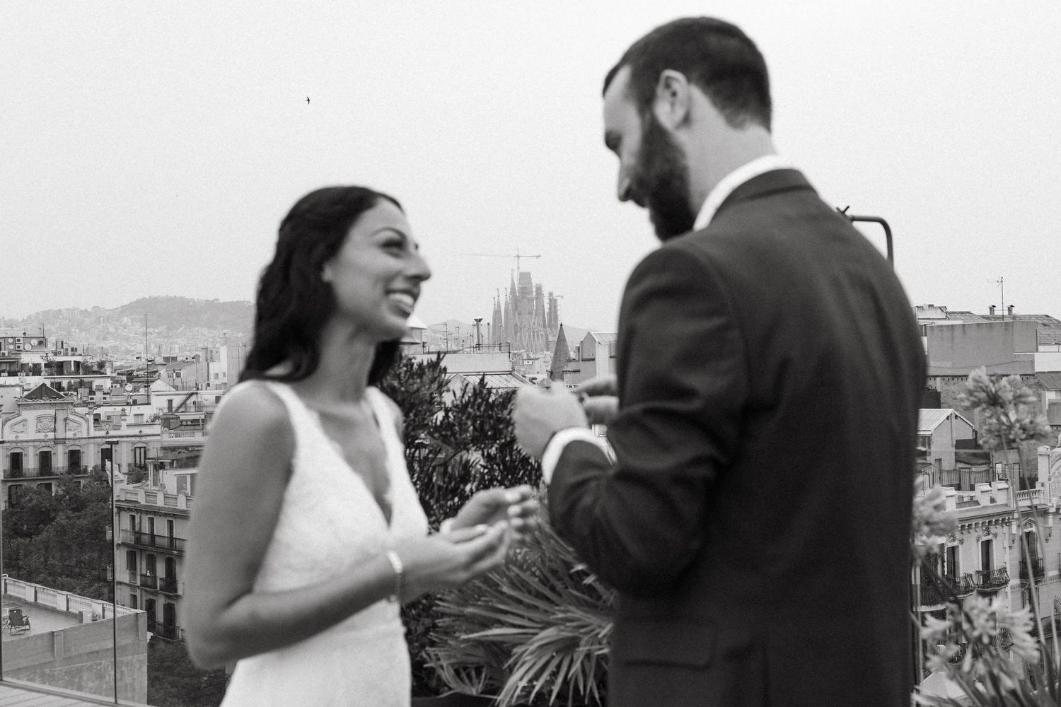 A couple shares intimate moments during a black and white photoshoot overlooking Barcelona's cityscape.