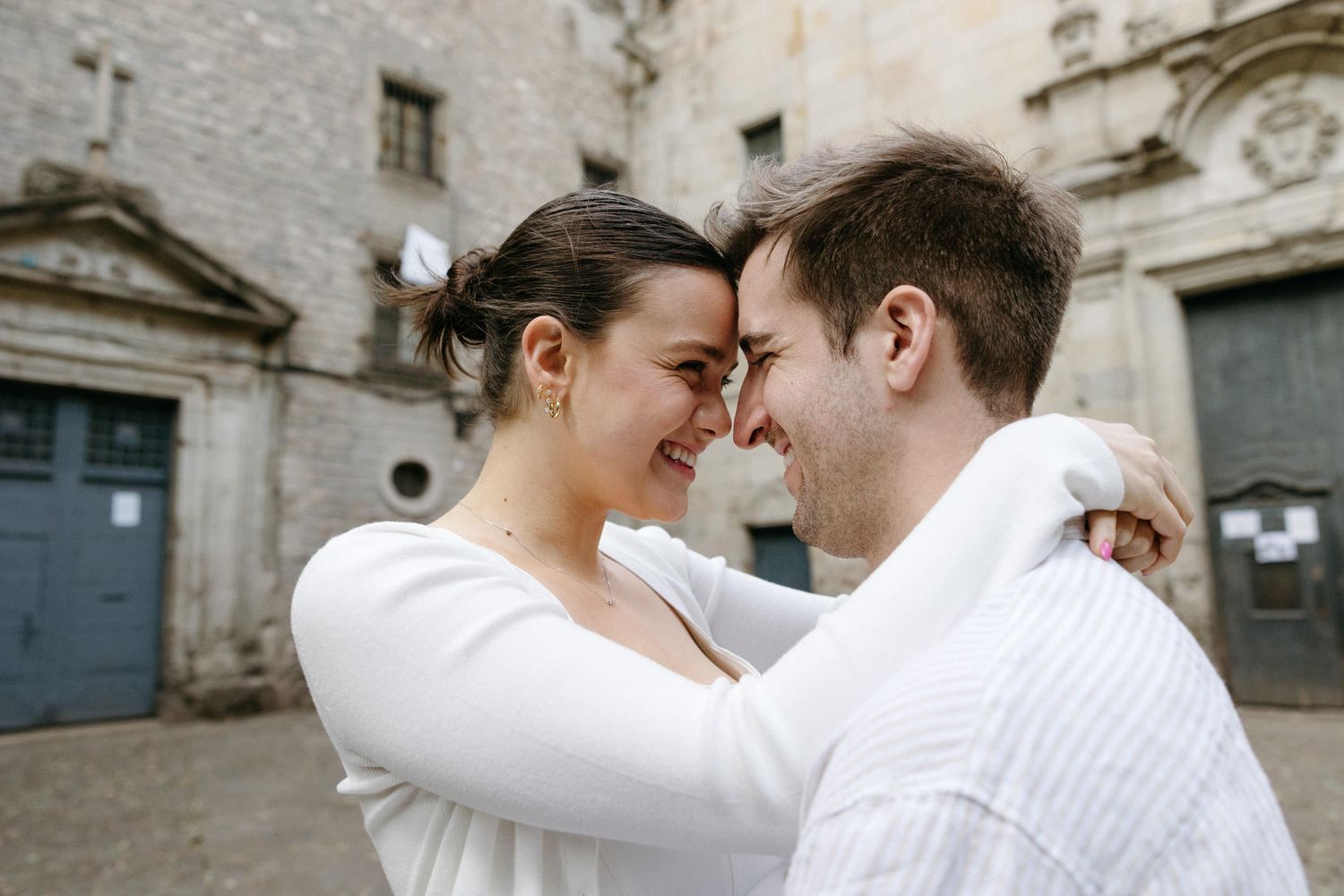 Romantic couple shares tender moments against a stone wall backdrop.