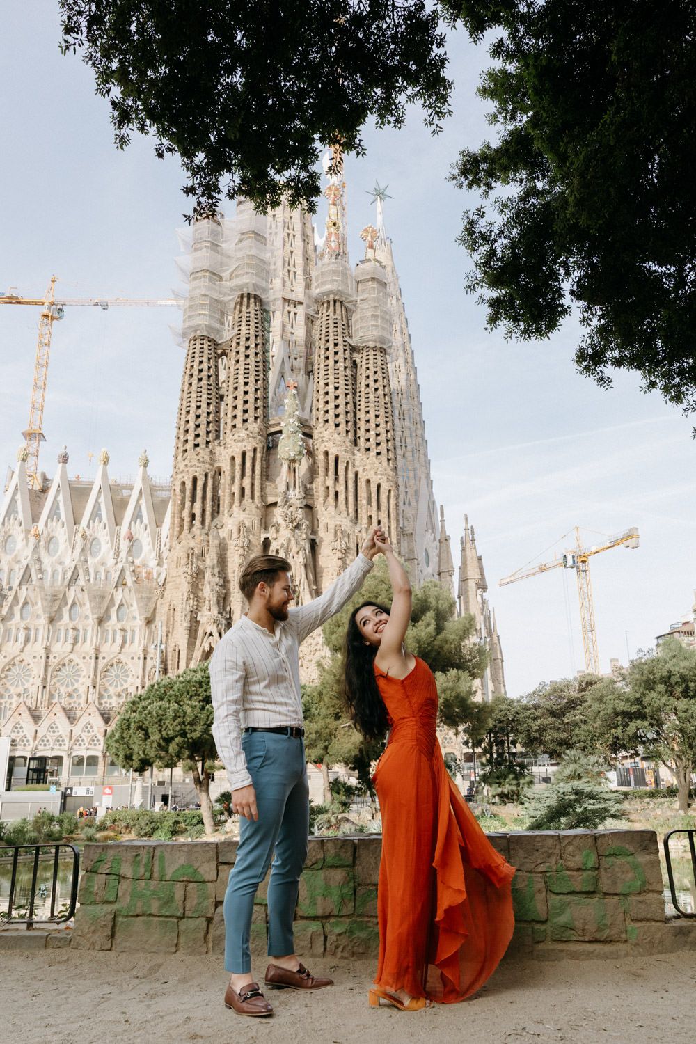 Couple poses romantically in front of the iconic Sagrada Familia cathedral in Barcelona.