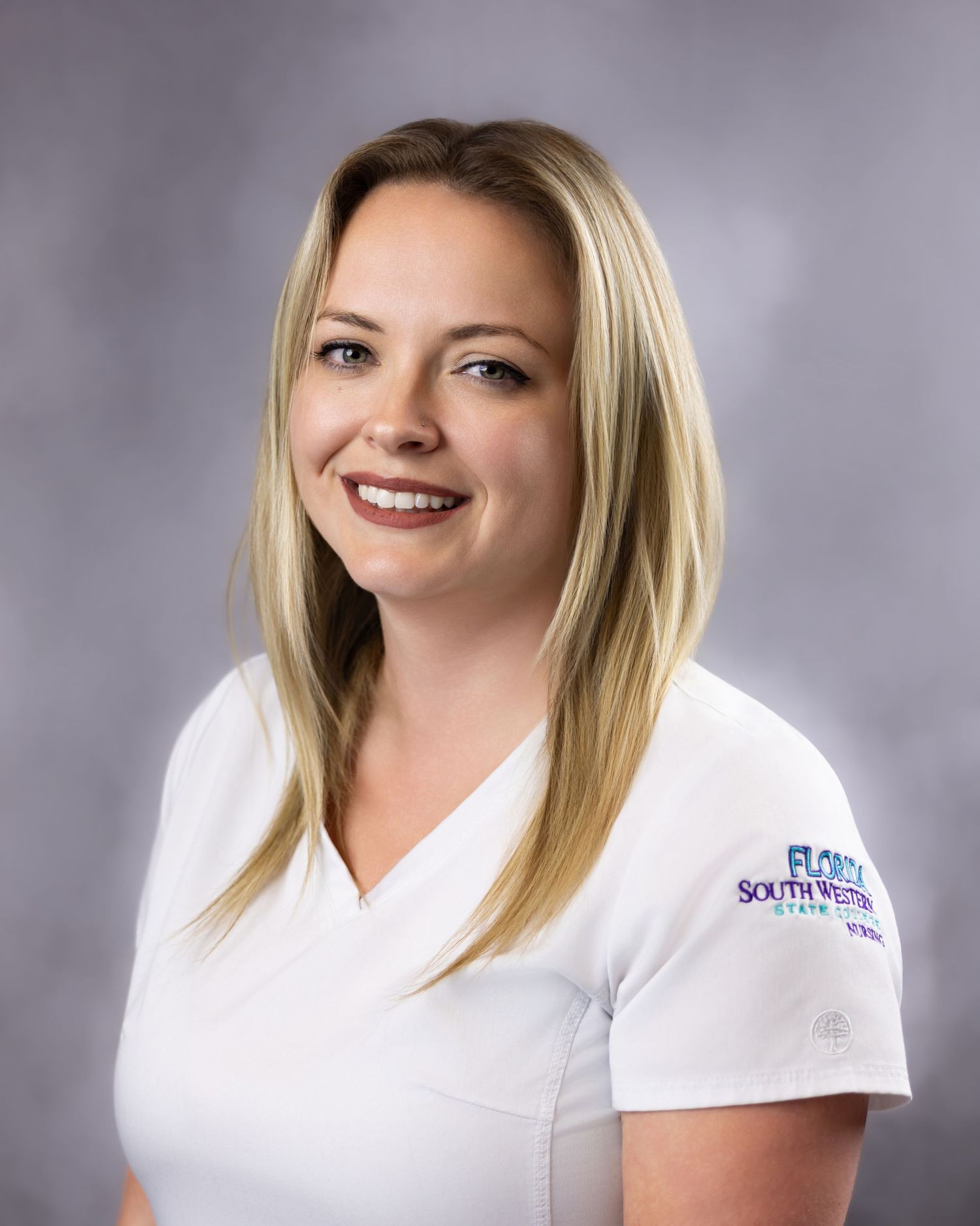 Smiling blonde woman in white Florida SouthWestern State College uniform shirt poses for professional headshot.