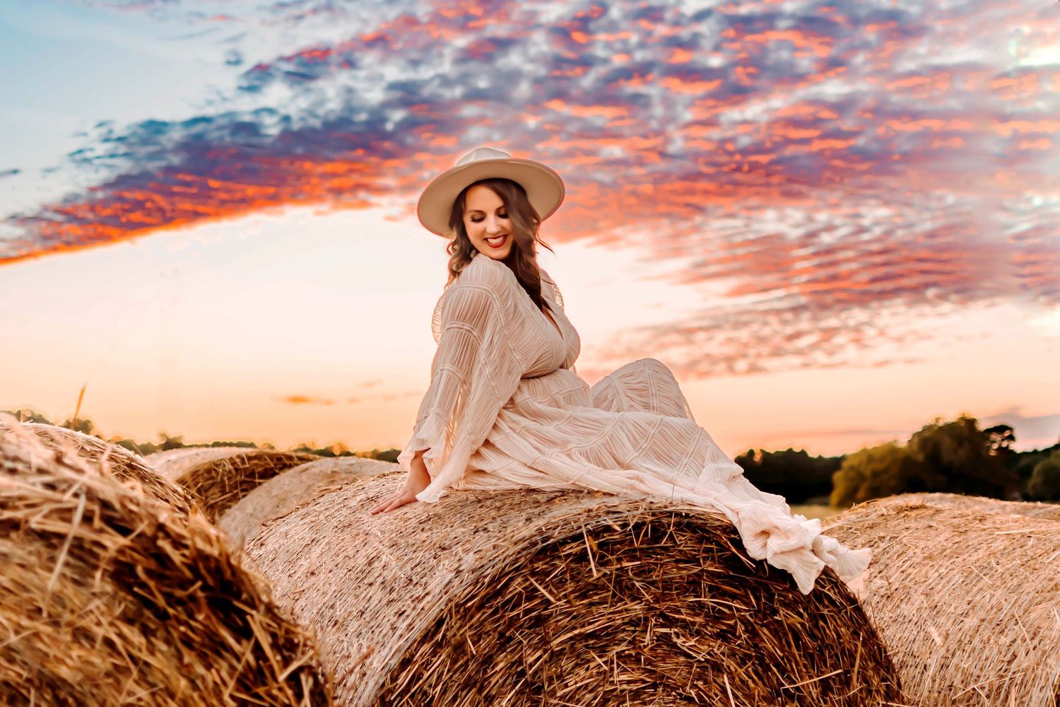 A romantic sunset photoshoot with clouds painted in vibrant pink and orange hues along a winding dirt road.