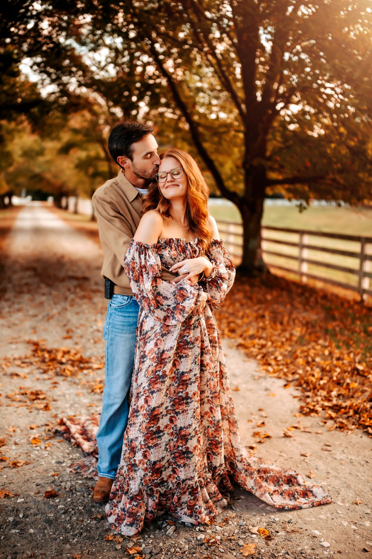 A romantic autumn photoshoot in a park with golden sunlight filtering through trees and fallen leaves on the ground.
