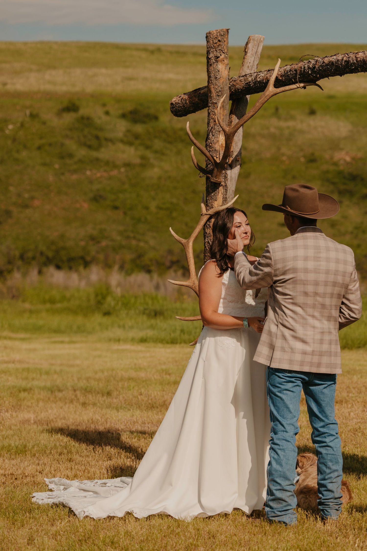 Montana Western Wedding photographer captures groom wiping tears from brides face. Elk antler arch. Paradise Valley Wedding Photographer