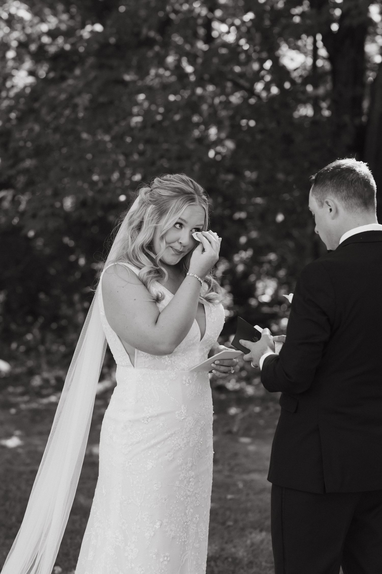 An emotional moment shared between a couple during their wedding ceremony in a wooded setting.
