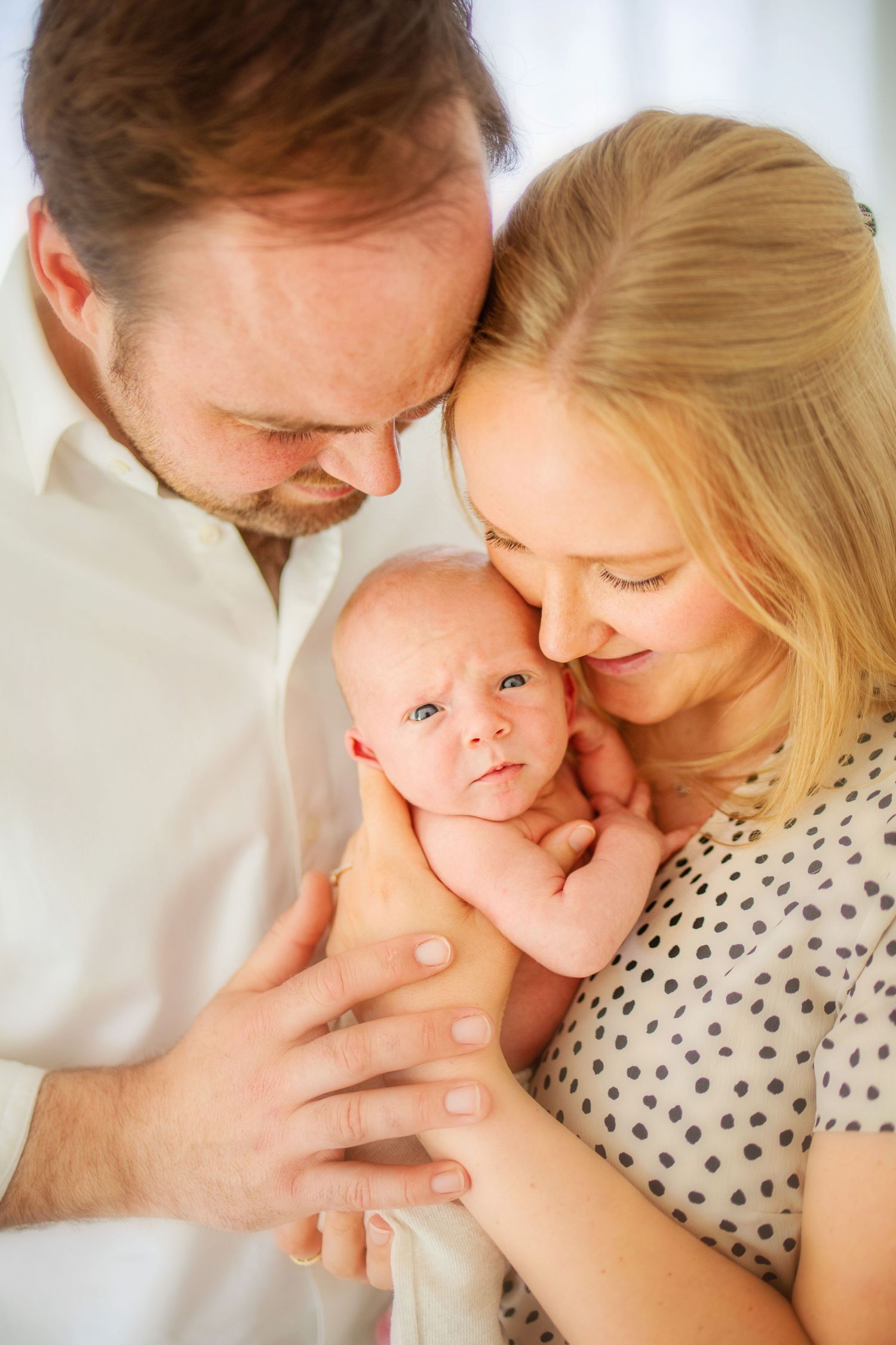 A series of tender family moments captured in soft lighting showing parents lovingly embracing their baby.