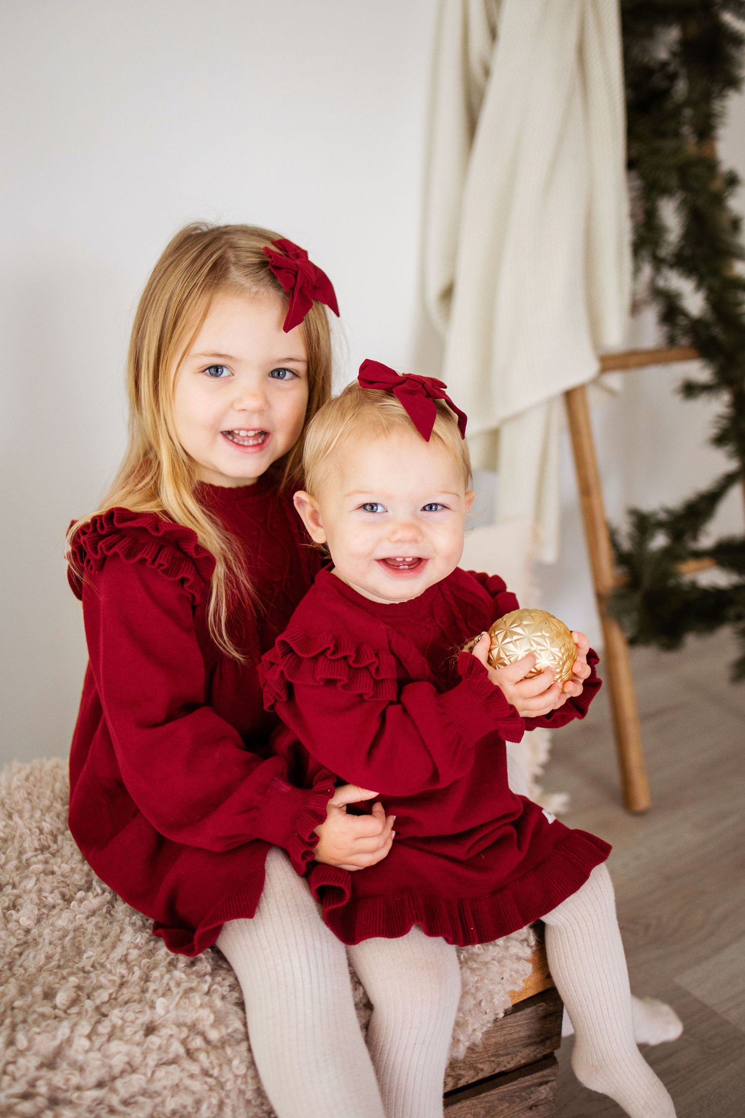 A child wearing a deep red ruffled dress and white tights sits on a wooden floor in a holiday photo collage.