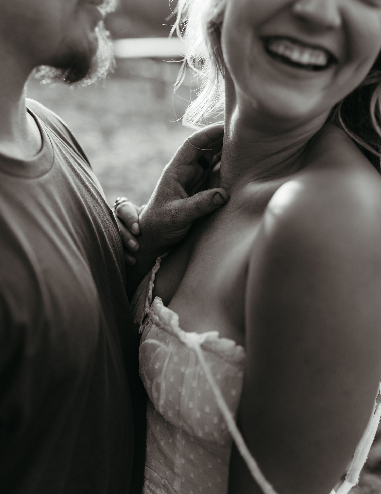 Black and white photo of laughing couple in intimate romantic outdoor moment.