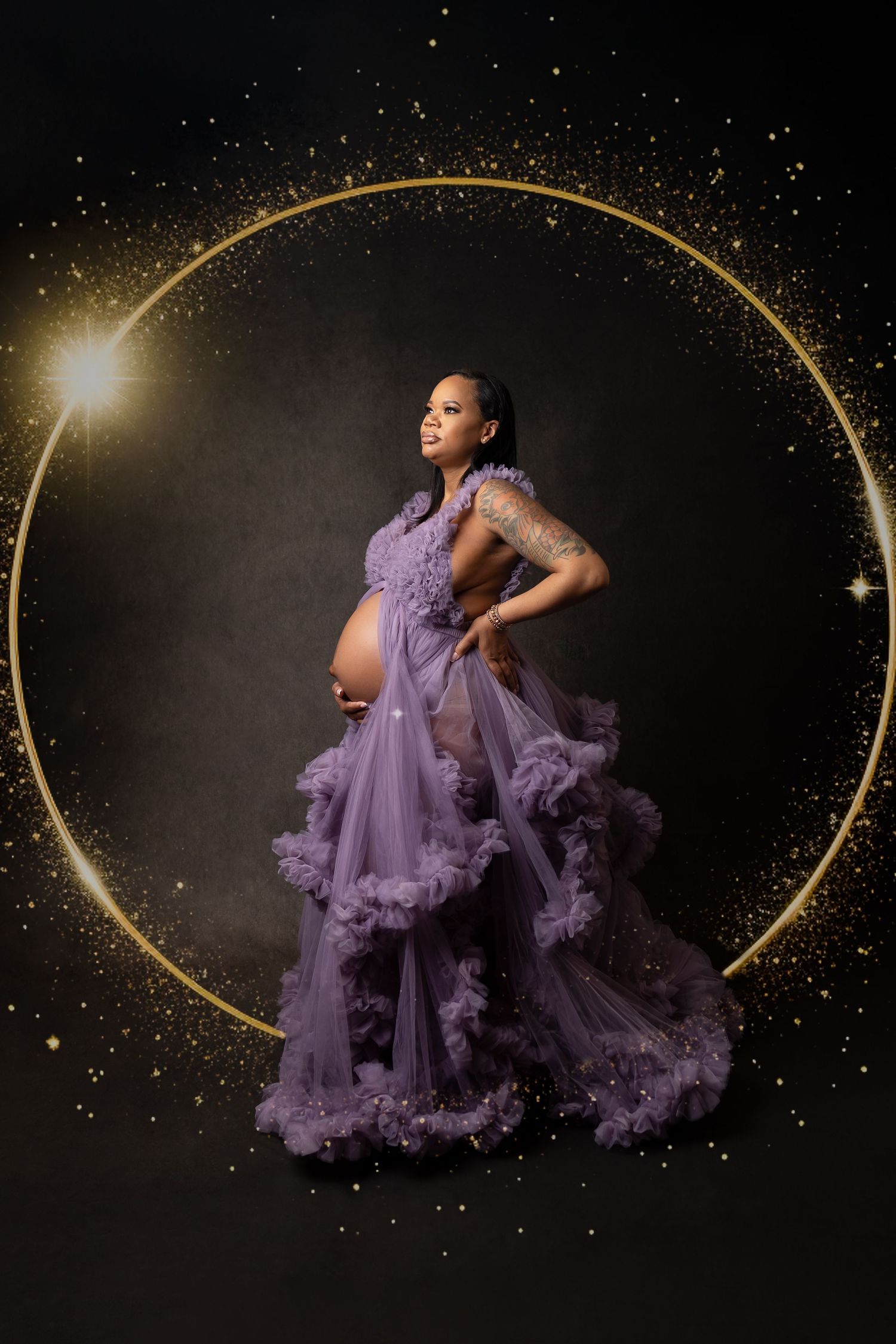Pregnant woman in lavender tulle gown poses inside golden circle with sparkling star backdrop.