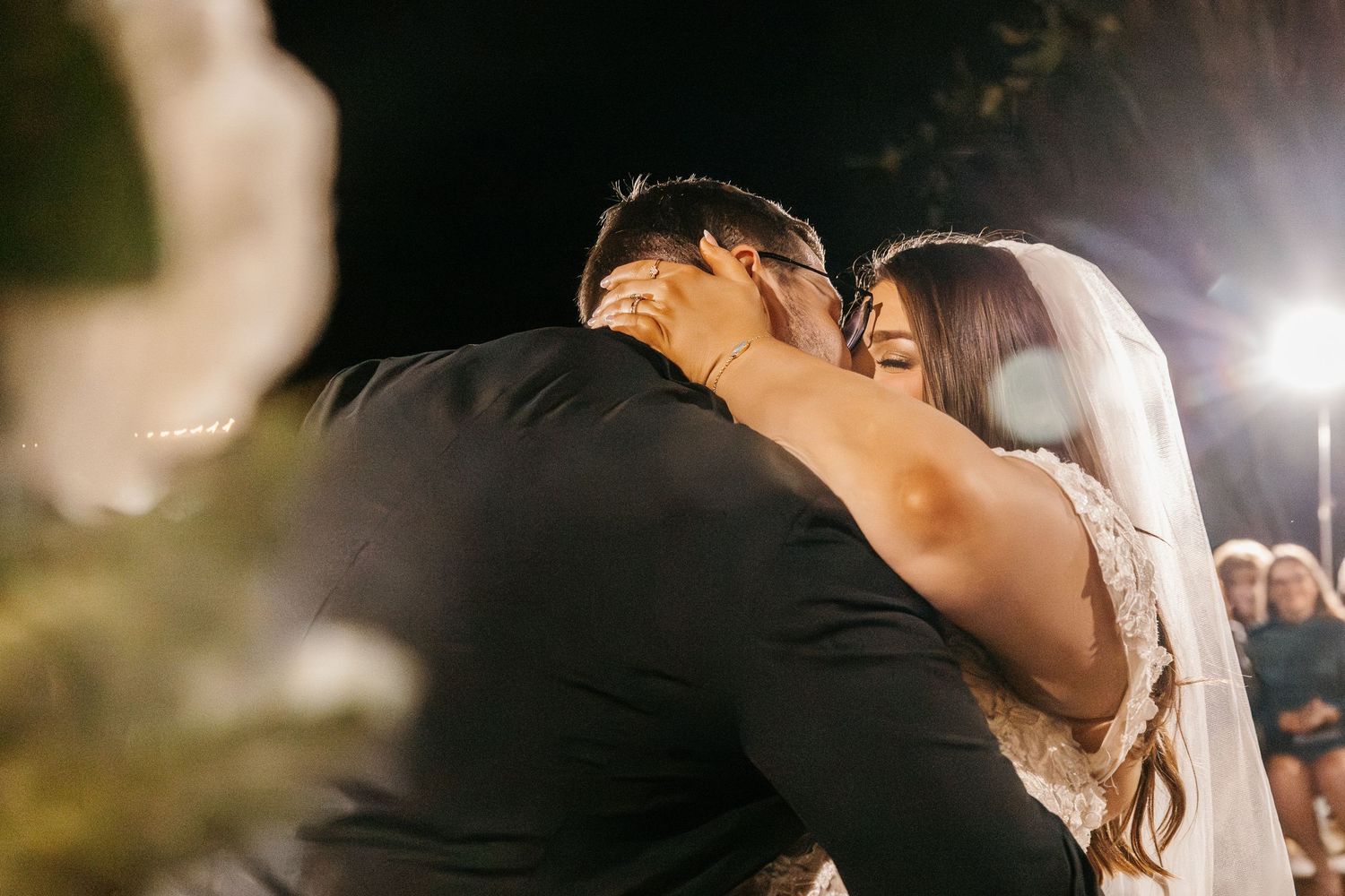 Bride and groom sharing first kiss at romantic outdoor wedding ceremony.