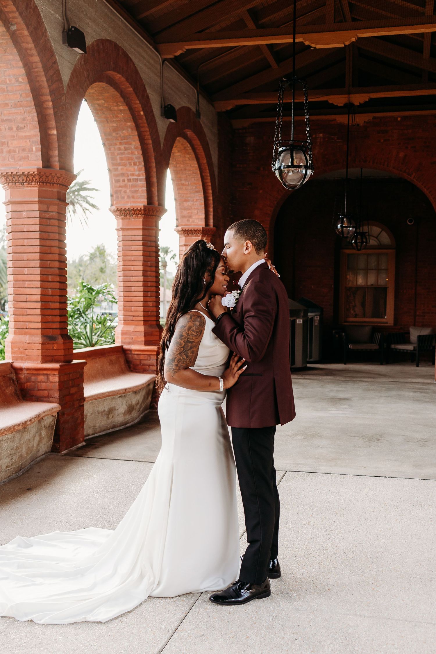 Bride and groom in an intimate embrace under warm brick archway at venue.