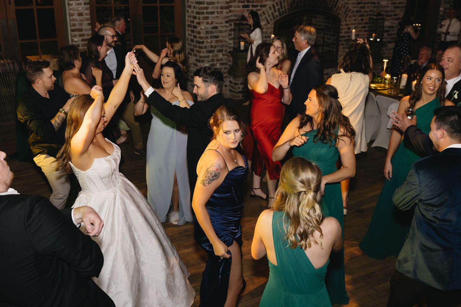 Guests dancing energetically on the dance floor at a lively indoor wedding reception celebration.