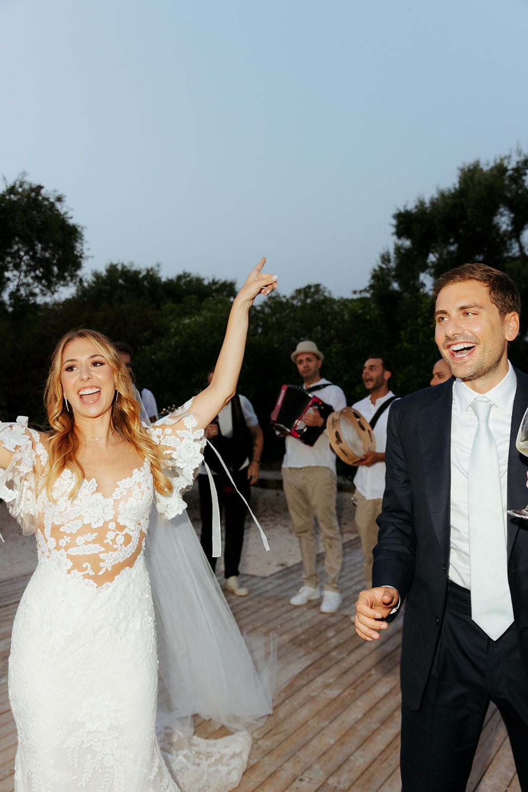Newlyweds dancing and celebrating joyfully on a wooden deck during their wedding reception.