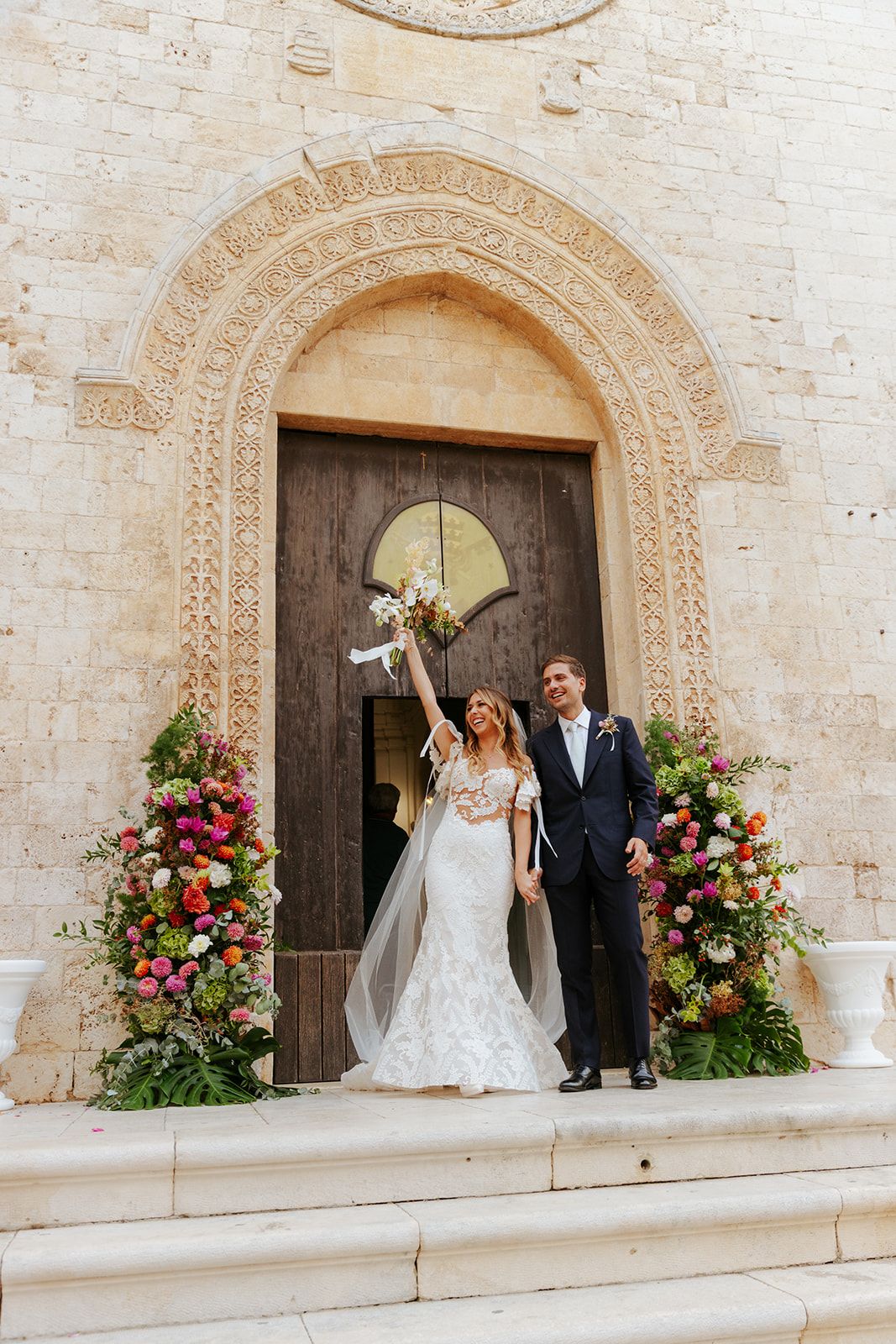 Series of wedding photos showing a couple emerging from an ornate stone church entrance decorated with pink and white flowers.