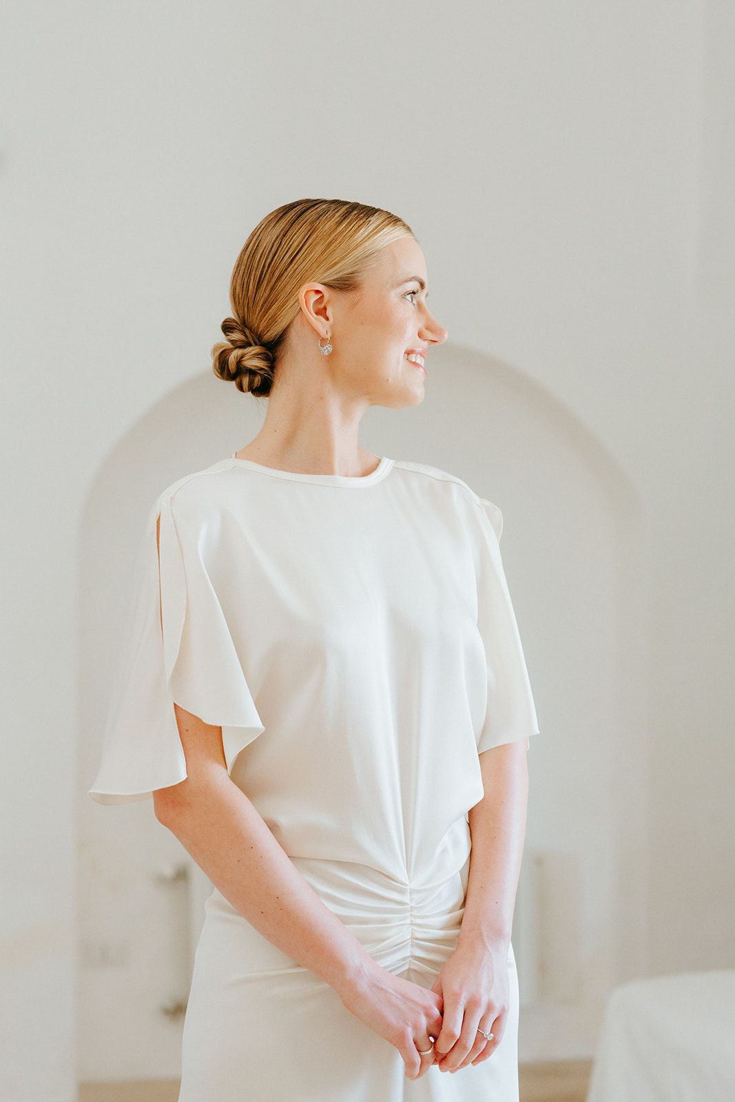 A person wearing a white short-sleeve top poses against a light gray background showing different angles.