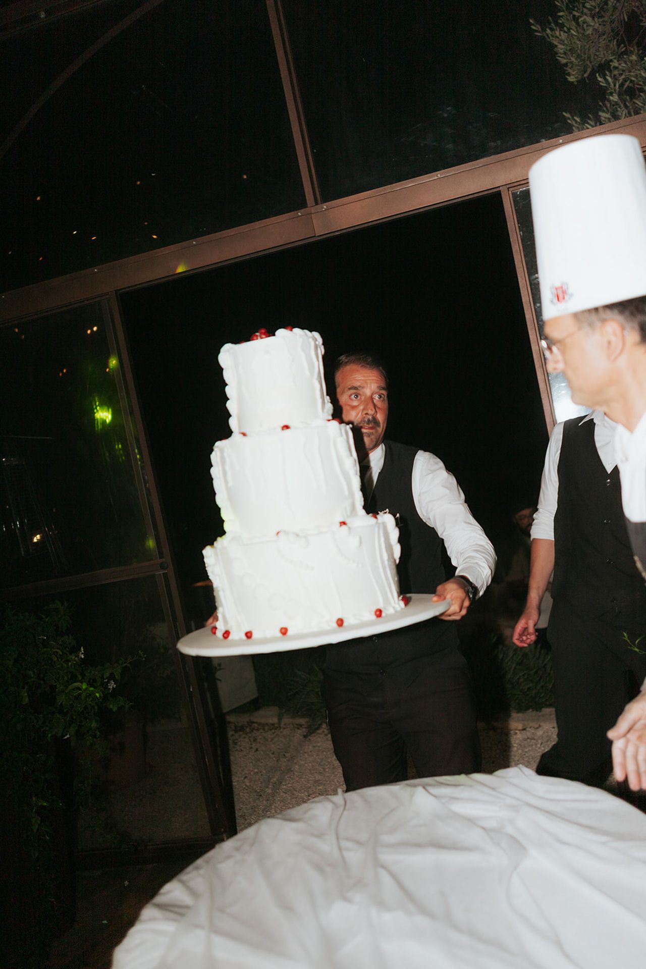 A sequence of photos showing a wedding cake being carried and accidentally dropped during a reception.