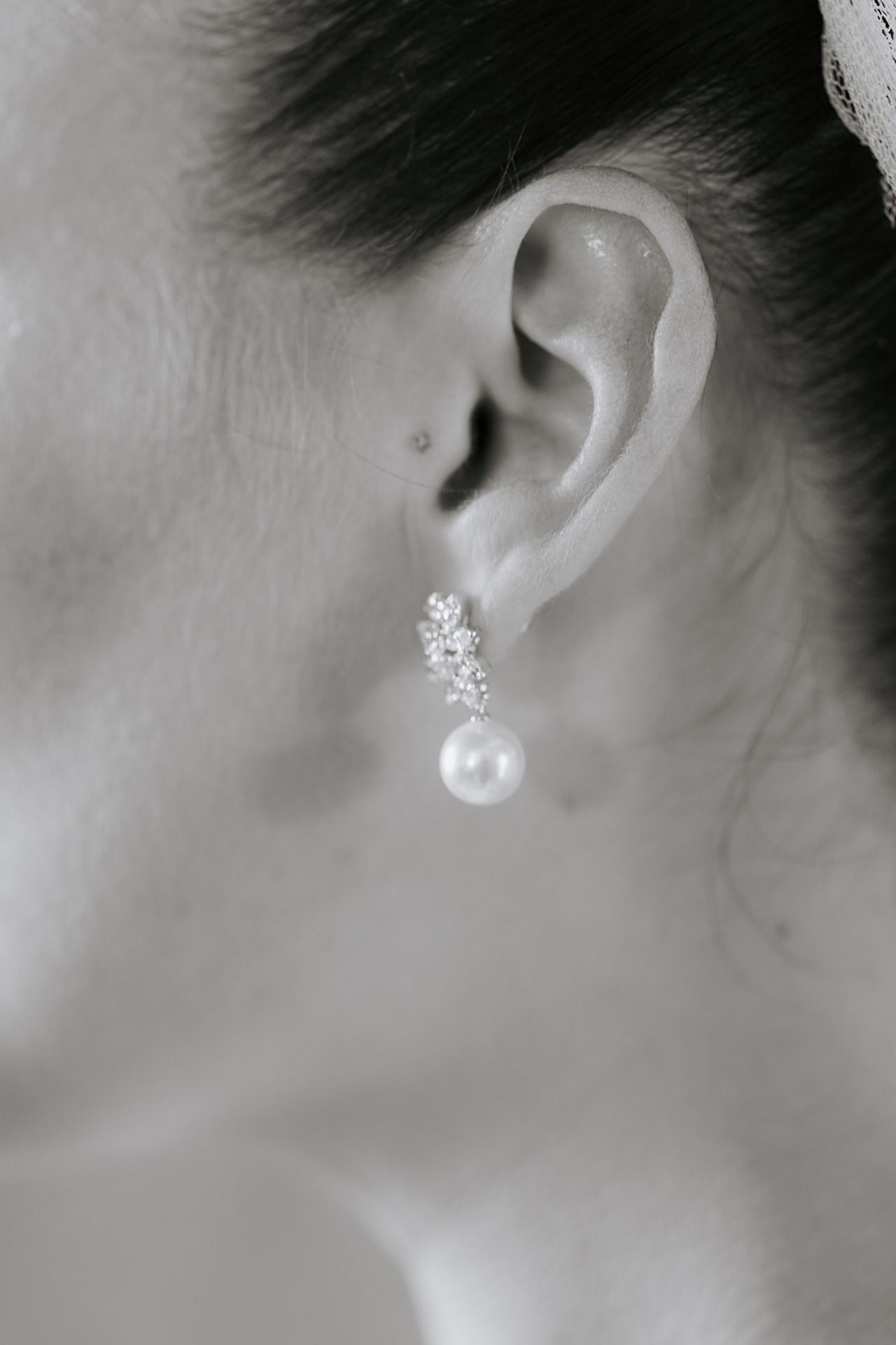Close-up view of delicate pearl and crystal stud earrings displayed on an ear.