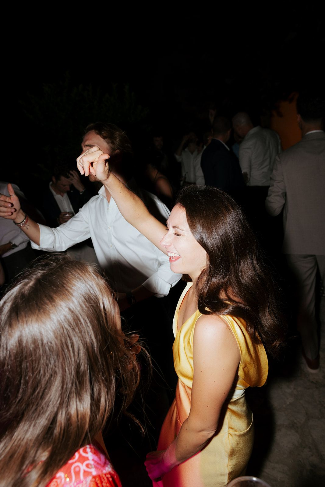 People dancing and enjoying themselves at a dimly lit party or nightclub while moving to the music.