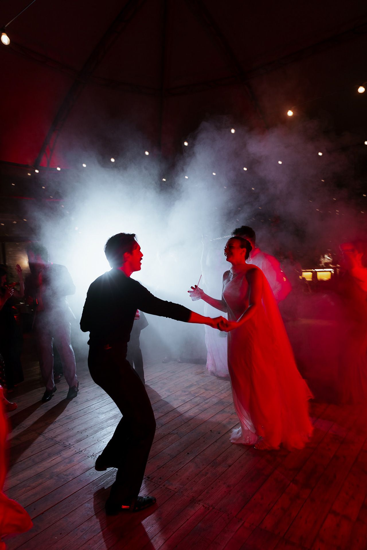 A couple dances in silhouette on a misty dance floor illuminated by dramatic red and white lighting effects.