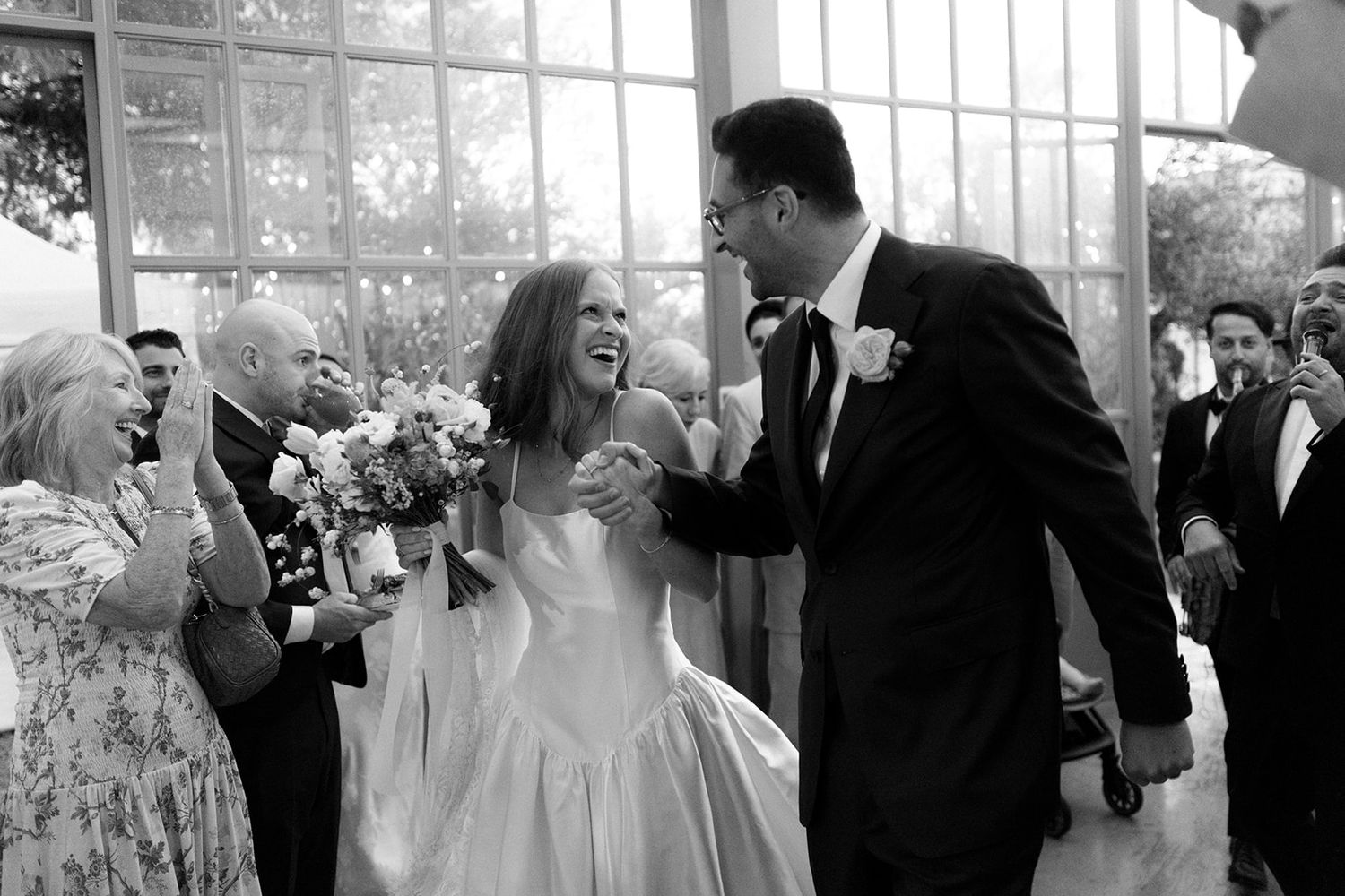 Black and white photo of wedding guests mingling during an elegant indoor celebration.