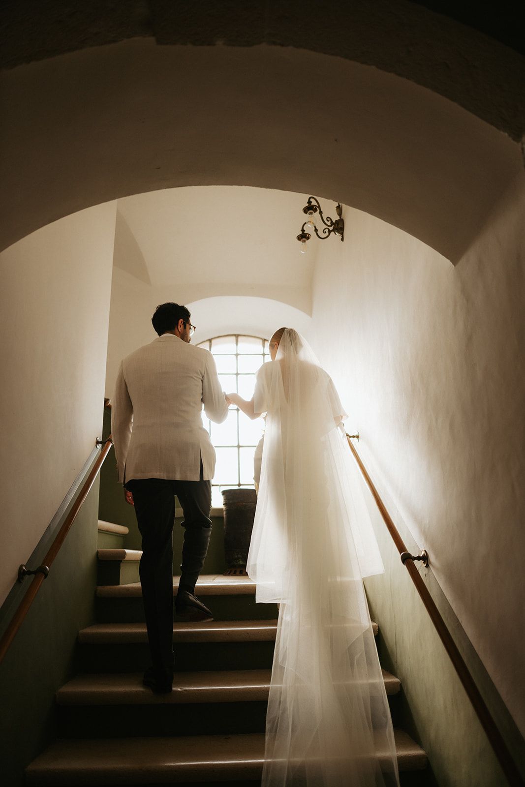 A sequence of silhouetted figures climbing dark stairs with ethereal white fabric creating a ghostly atmosphere.