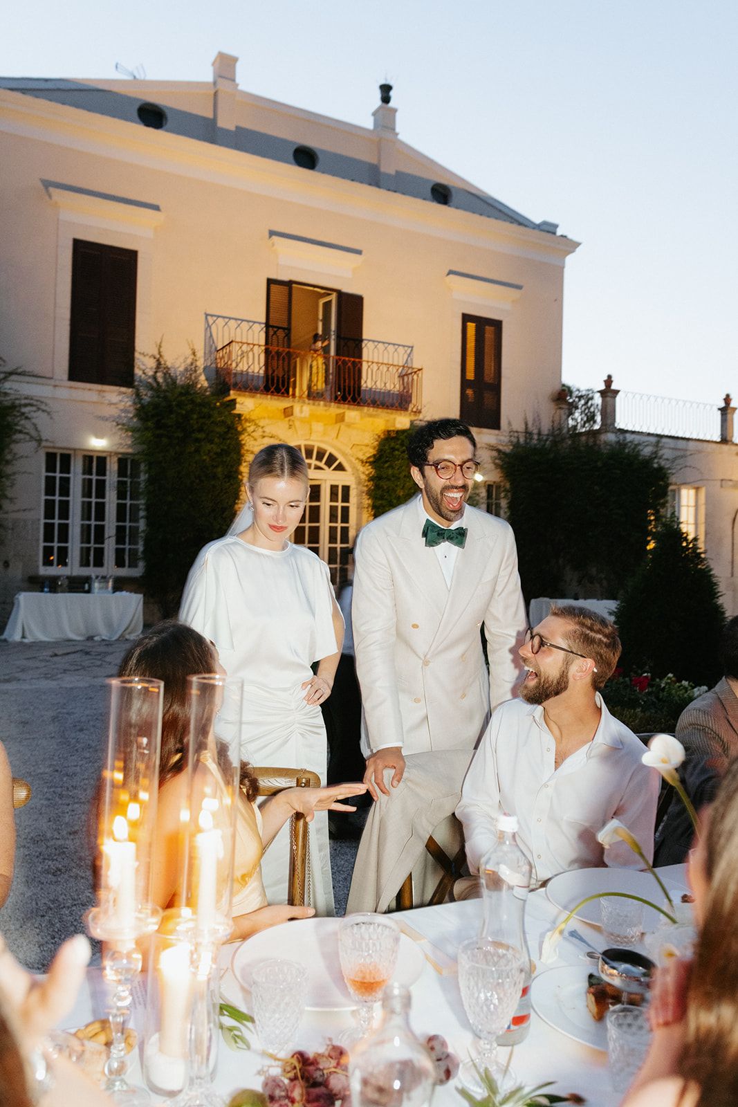 Elegant outdoor evening dinner party at a Mediterranean villa with candlelit table and festive atmosphere.