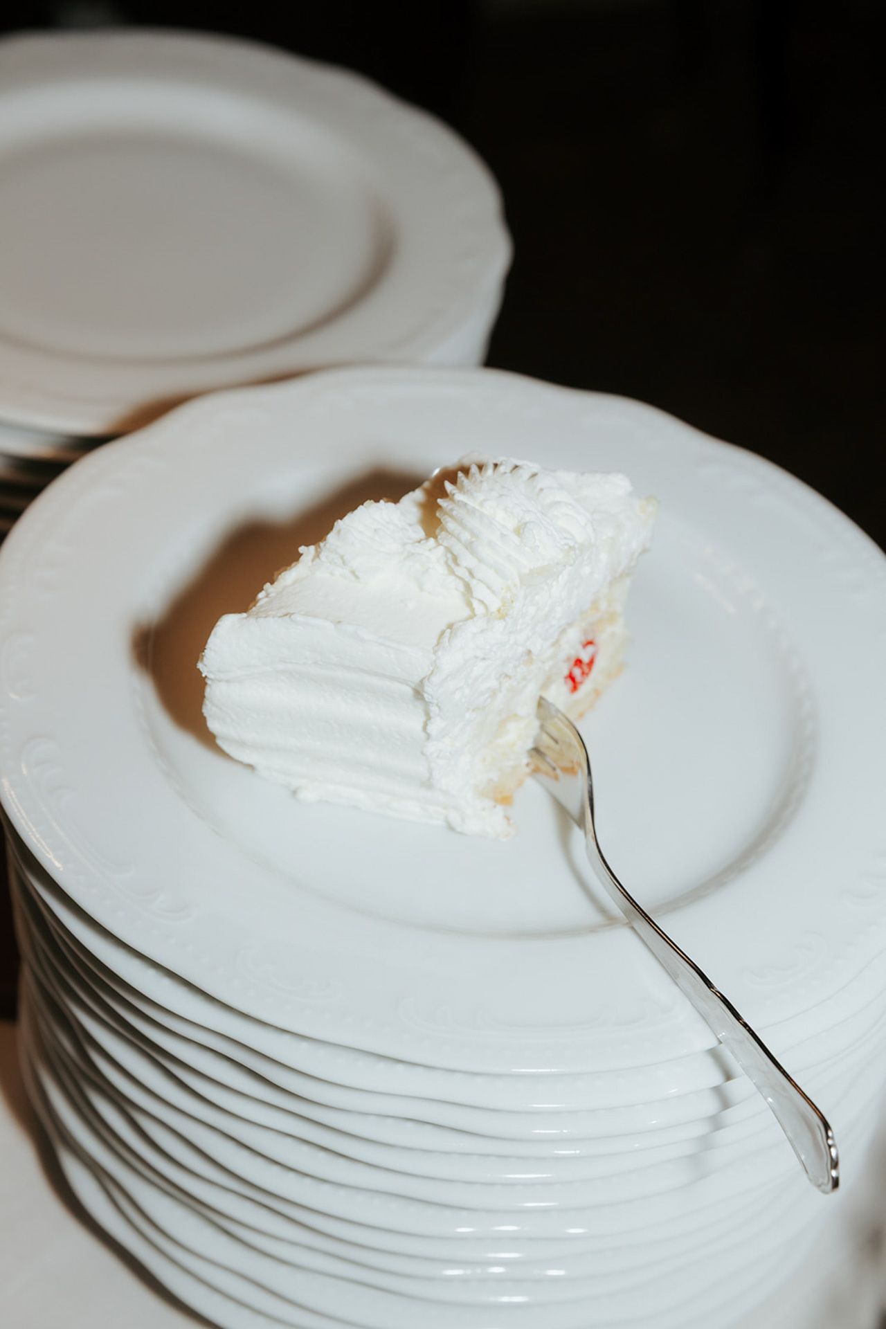 A stack of white ceramic plates with a small portion of whipped cream or frosting on top of the uppermost plate.