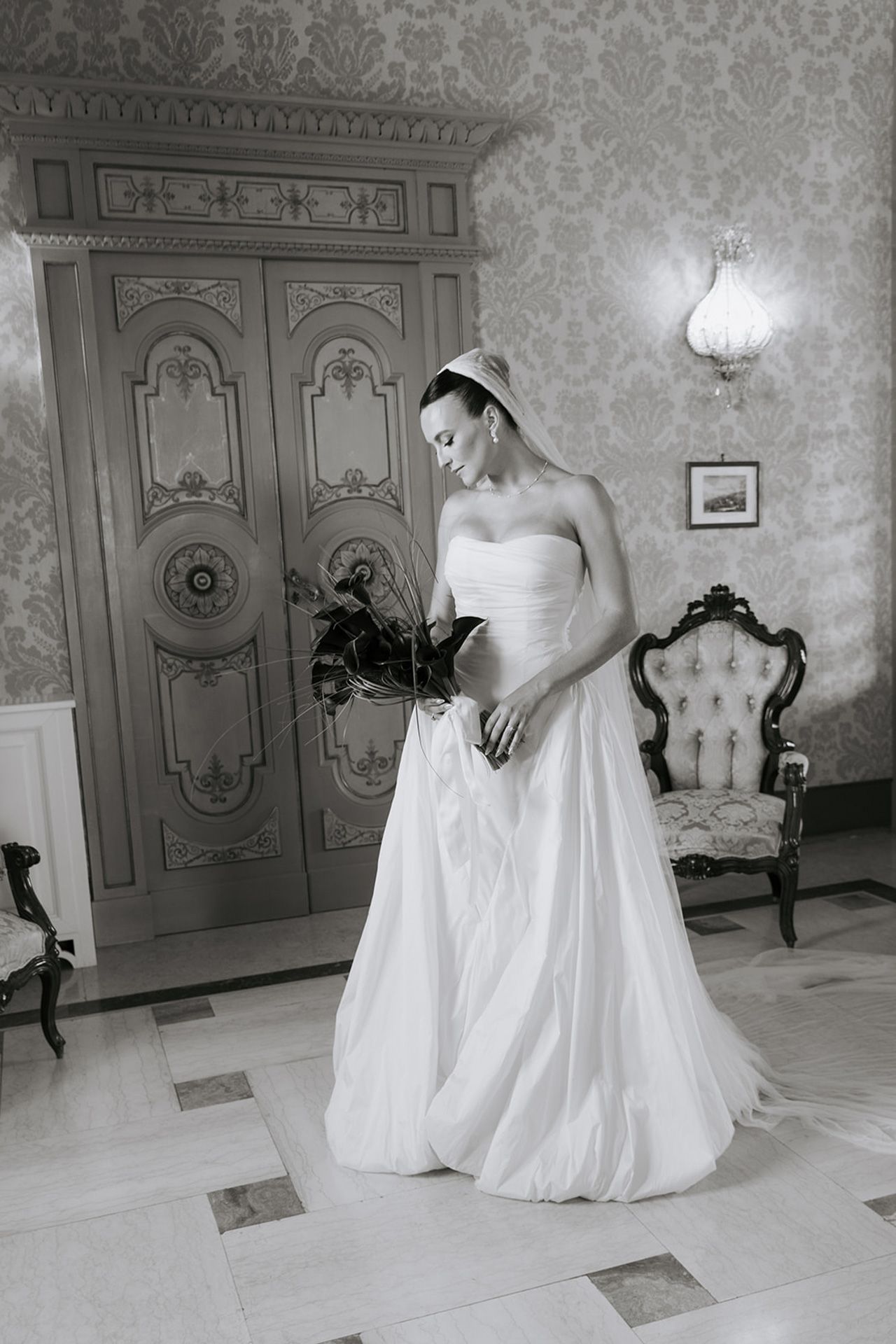A wedding dress is displayed in an elegant room with ornate wall panels and classical decor.