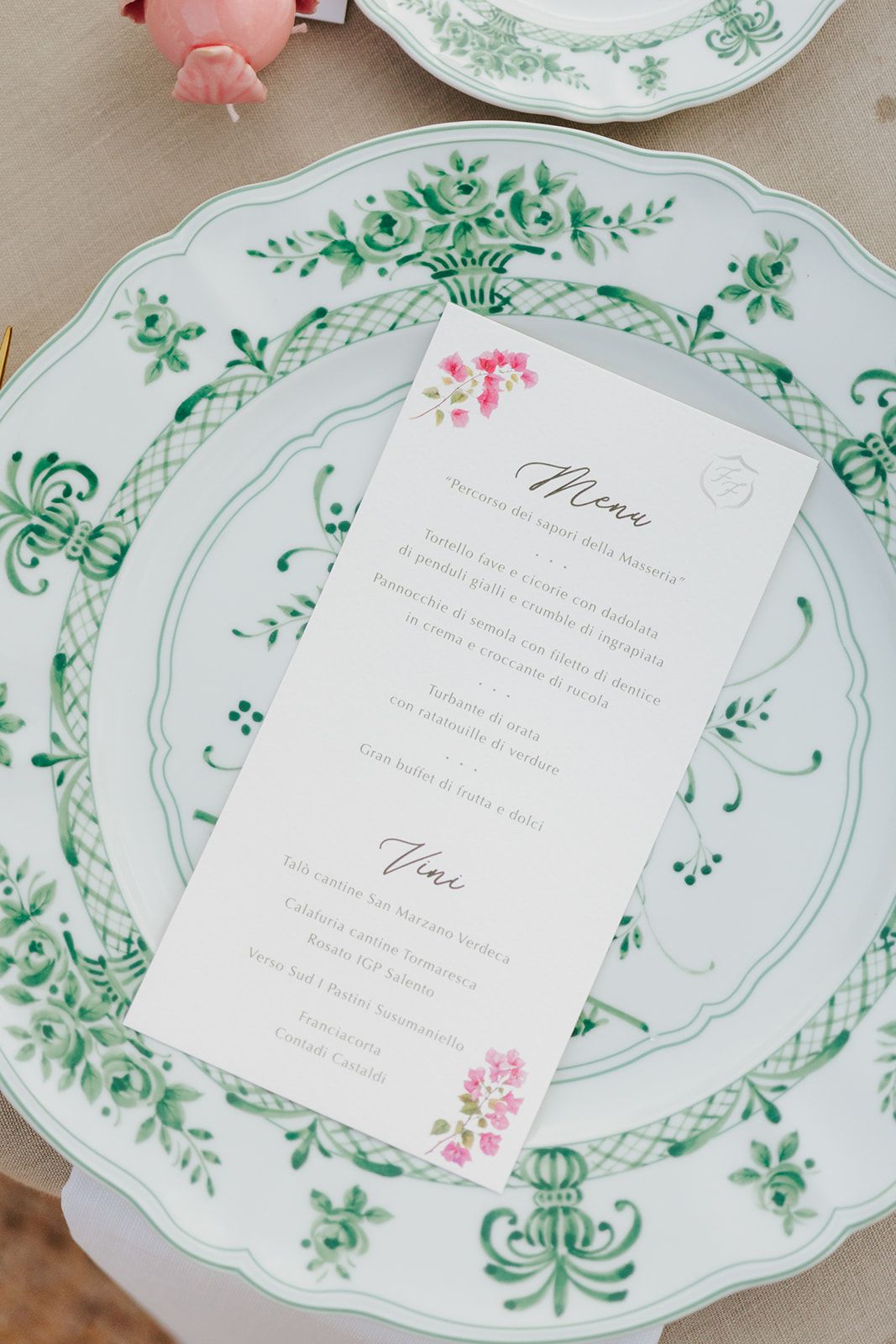 An elegant wedding menu card displayed on a vintage green and white floral patterned china plate.