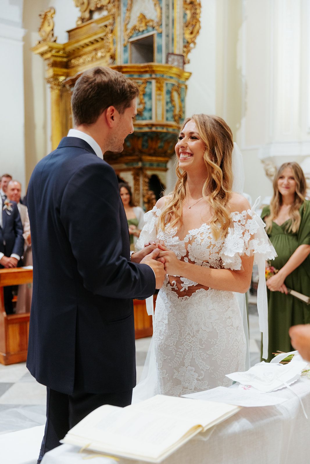 A joyful wedding couple shares their first dance in an ornate church with golden decor and white walls.