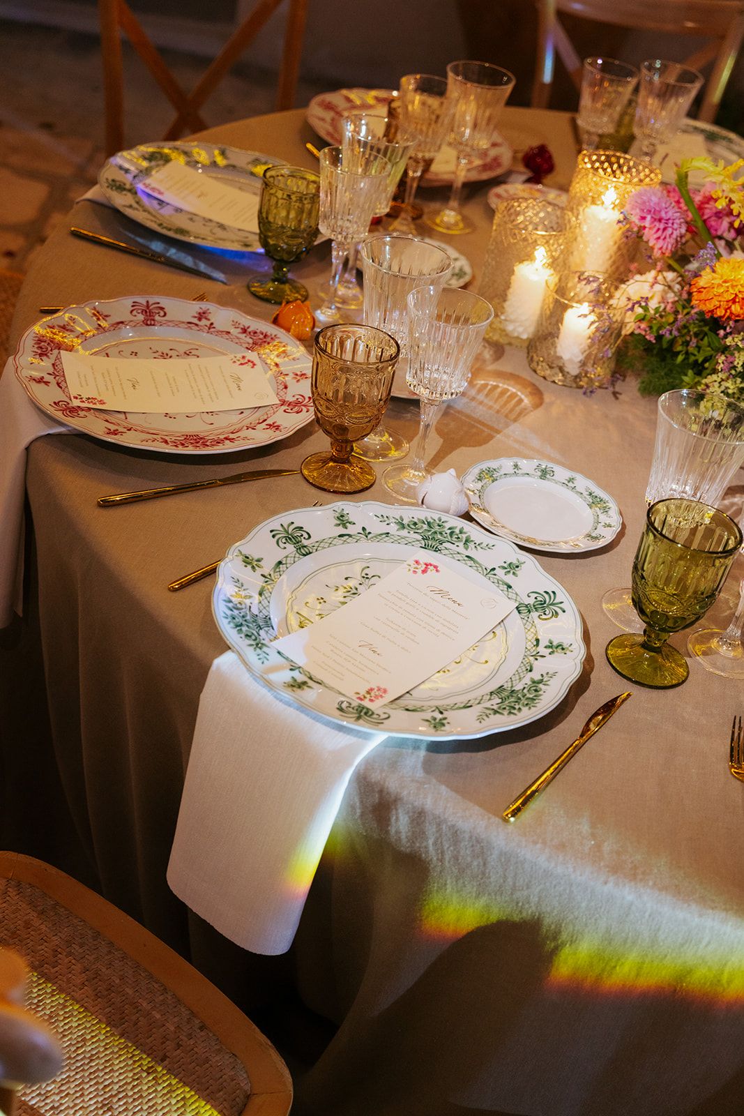 Elegant dining table setting with decorative china plates, vintage glassware, and soft candlelight creating a romantic ambiance.